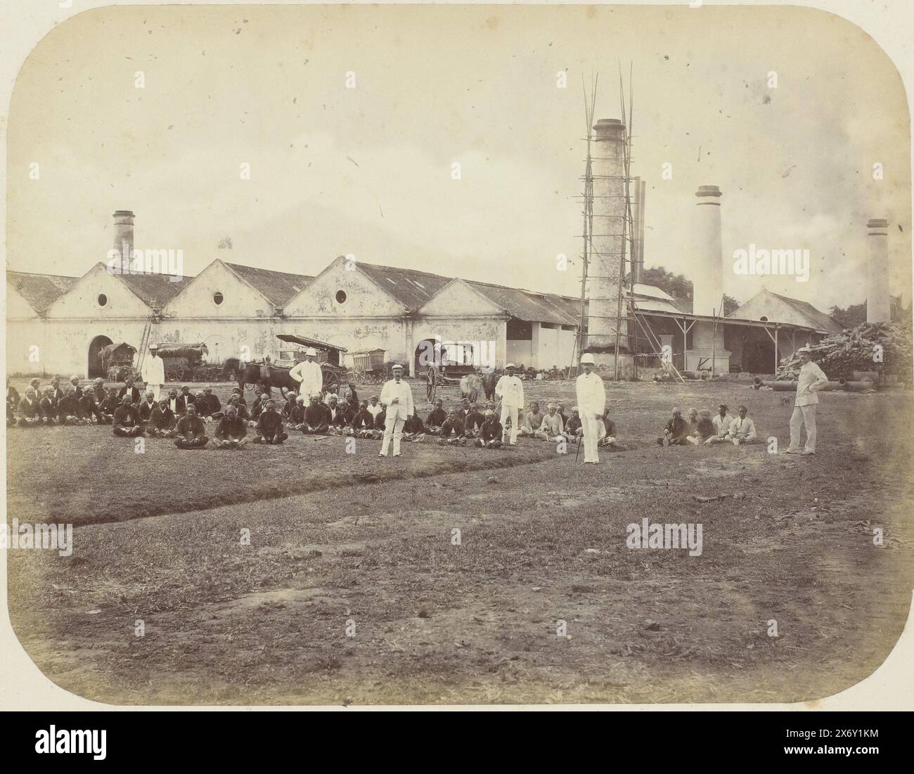 Eine Zuckerfabrik, Eine Zuckerfabrik mit sechs Schornsteinen, von denen einer im Gerüst ist. Im Vordergrund ein Rasen mit stehenden Europäern und sitzenden javanischen Arbeitern. Teil des Fotoalbums, das von der Soerabayasche Association of Suikerfabrikanten an Frederik Beyerinck, Einwohner von Soerabaya, präsentiert wurde., Foto, Herman Salzwedel, Soerabayasche Vereeniging van Suikerfabrikanten, Surabaya, 1876 - 1884, fotografische Unterstützung, Albumendruck, Höhe, 21,8 cm x Breite, 28,4 cm Stockfoto