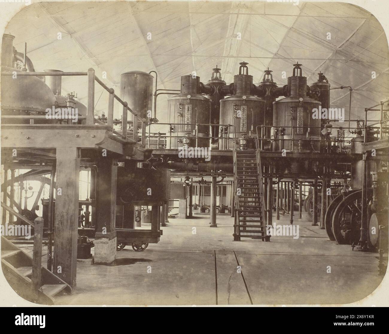 Das Innere einer Zuckerfabrik, das Innere einer Zuckerfabrik mit einer zentralen, geraden Eisentreppe, die zu einem Boden mit einer Reihe von Druckkesseln und Reservetanks führt. Teil des Fotoalbums, das von der Soerabayasche Association of Suikerfabrikanten an Frederik Beyerinck, Einwohner von Soerabaya, präsentiert wurde., Foto, Herman Salzwedel, Soerabayasche Vereeniging van Suikerfabrikanten, Surabaya, 1876 - 1884, fotografische Unterstützung, Albumendruck, Höhe, 22,8 cm x Breite, 29,1 cm Stockfoto