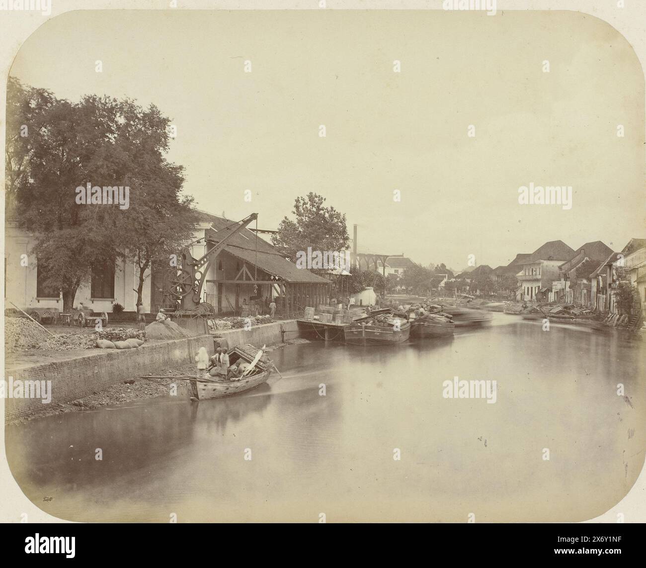 Blick auf die Kali Mas in Surabaya, Blick auf die Kali Mas in Surabaya mit einem Lastkahn mit Figuren auf der linken Seite und einer Reihe von festgemachten Schiffen. Links eine Fabrik mit Kran und rechts eine Reihe Häuser am Fluss. Teil des Fotoalbums, das von der Soerabayasche Association of Suikerfabrikanten an Frederik Beyerinck, Einwohner von Soerabaya, präsentiert wurde., Foto, Herman Salzwedel, Soerabayasche Vereeniging van Suikerfabrikanten, Surabaya, 1876 - 1884, fotografische Unterstützung, Albumendruck, Höhe, 21,8 cm x Breite, 27,2 cm Stockfoto