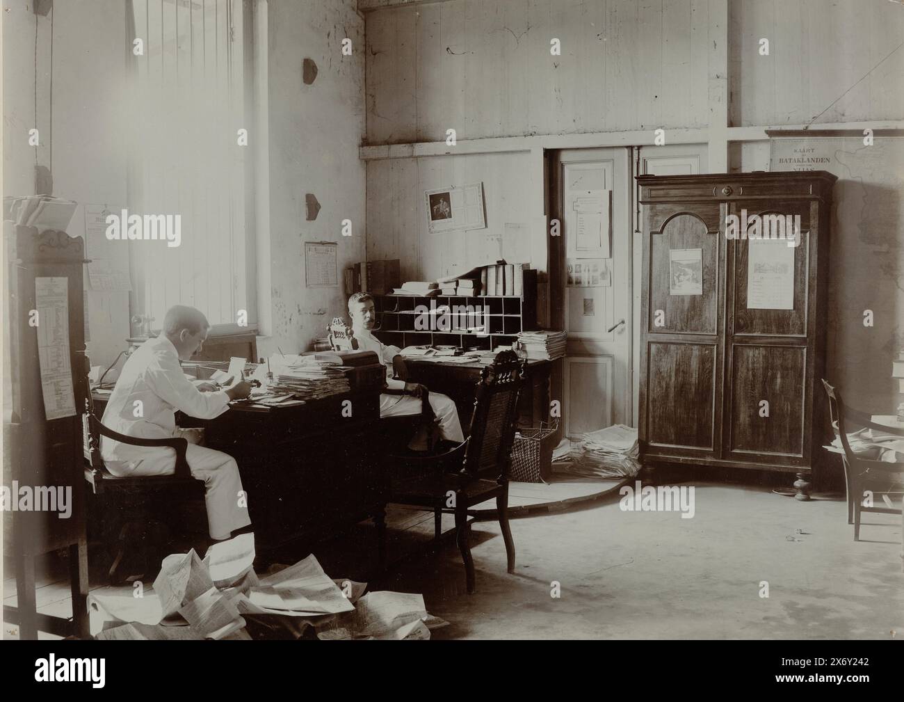 Redaktionssaal des Deli Courant, der Redaktionssaal des Deli Courant in Medan, mit zwei Redakteuren, die hinter ihren Schreibtischen sitzen. Teil einer separaten Gruppe von neun Fotos aus dem Jahr 1908 innerhalb der gesamten Gruppe von 49 losen Schwarzweißfotos unterschiedlicher Größe über das Verlags- und Druckwerk der Zeitung Deli Courant in Medan im Zeitraum 1885-1947., Foto, anonym, (auf Objekt erwähnt), Medan, Aug-1908 - Okt-1908, fotografischer Träger, Höhe, 210 mm x Breite, 293 mm Stockfoto