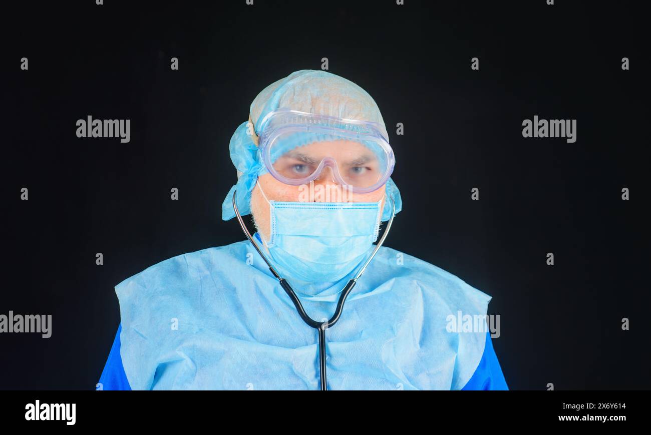 Medizinisches Personal. Porträt des ernsthaften Arztes in Schutzmaske, Schutzbrille und Einweg-OP-Kappe mit Stethoskop. Krankenhauspersonal in medizinischer Uniform Stockfoto