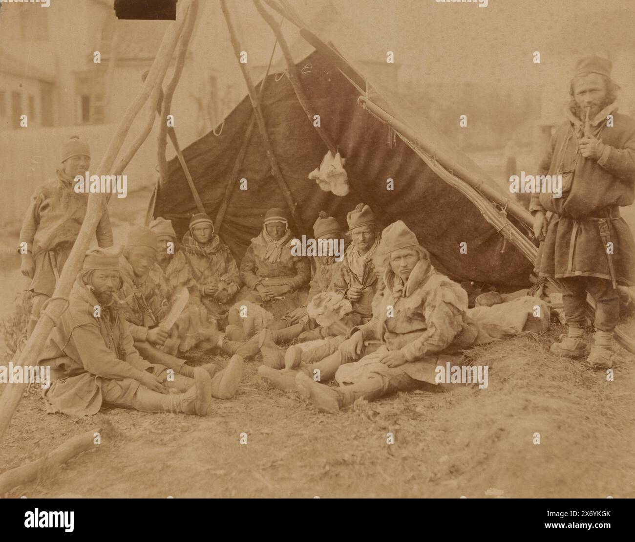 Gruppenporträt des unbekannten Sami hinter einer Windschutzscheibe, Foto, anonym, Sápmi, 1860 - 1900, Papier, Albumendruck, Höhe, 225 mm x Breite, 284 mm Stockfoto