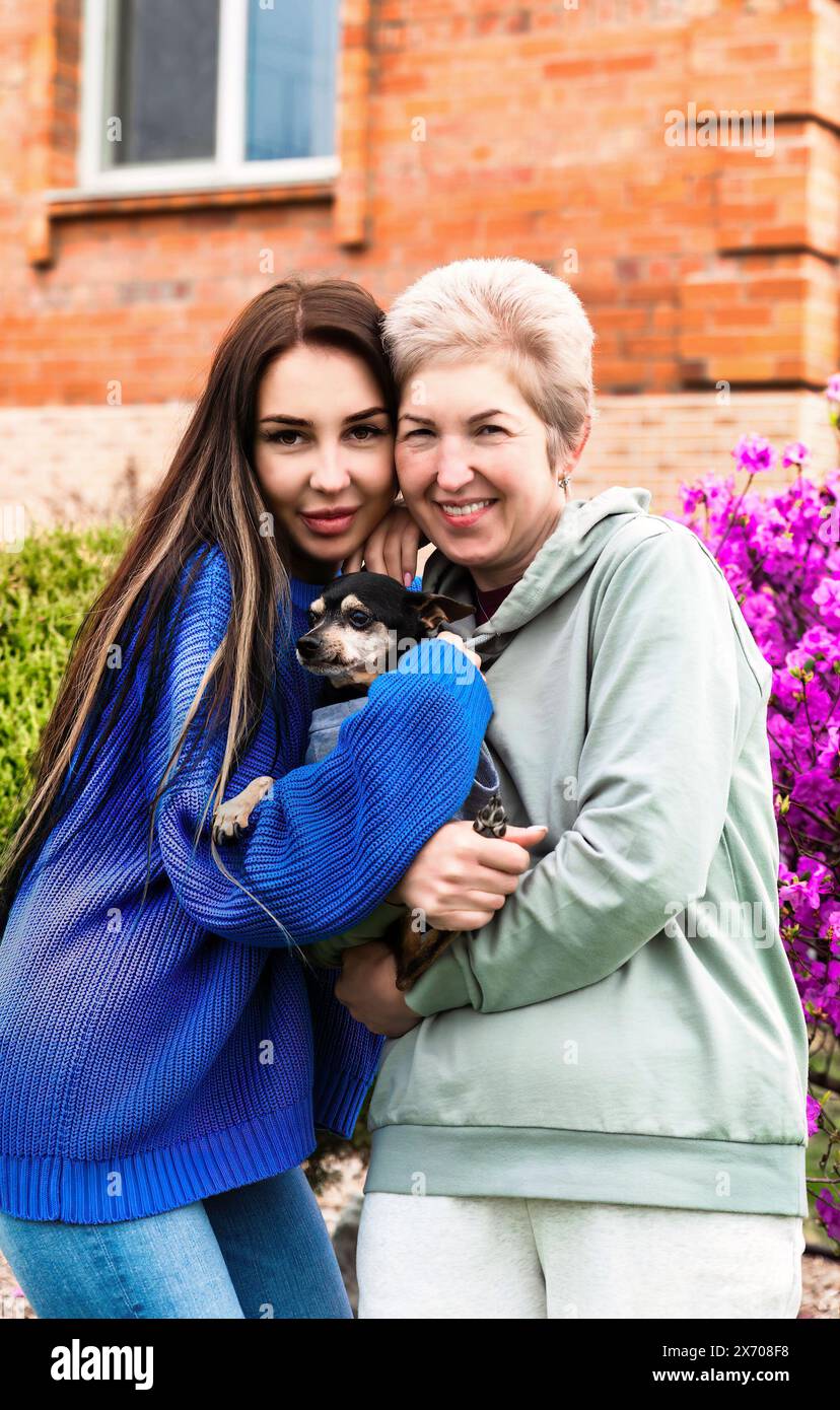 Porträt der Schwiegertochter umarmt Schwiegermutter und hält Hund Stockfoto