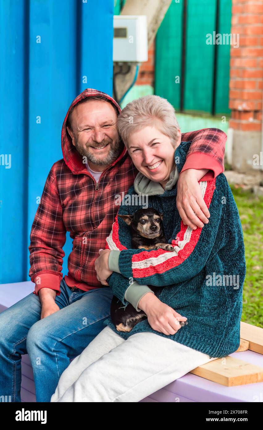 Reifes russisches Ehepaar umarmt und hält einen Hund Stockfoto