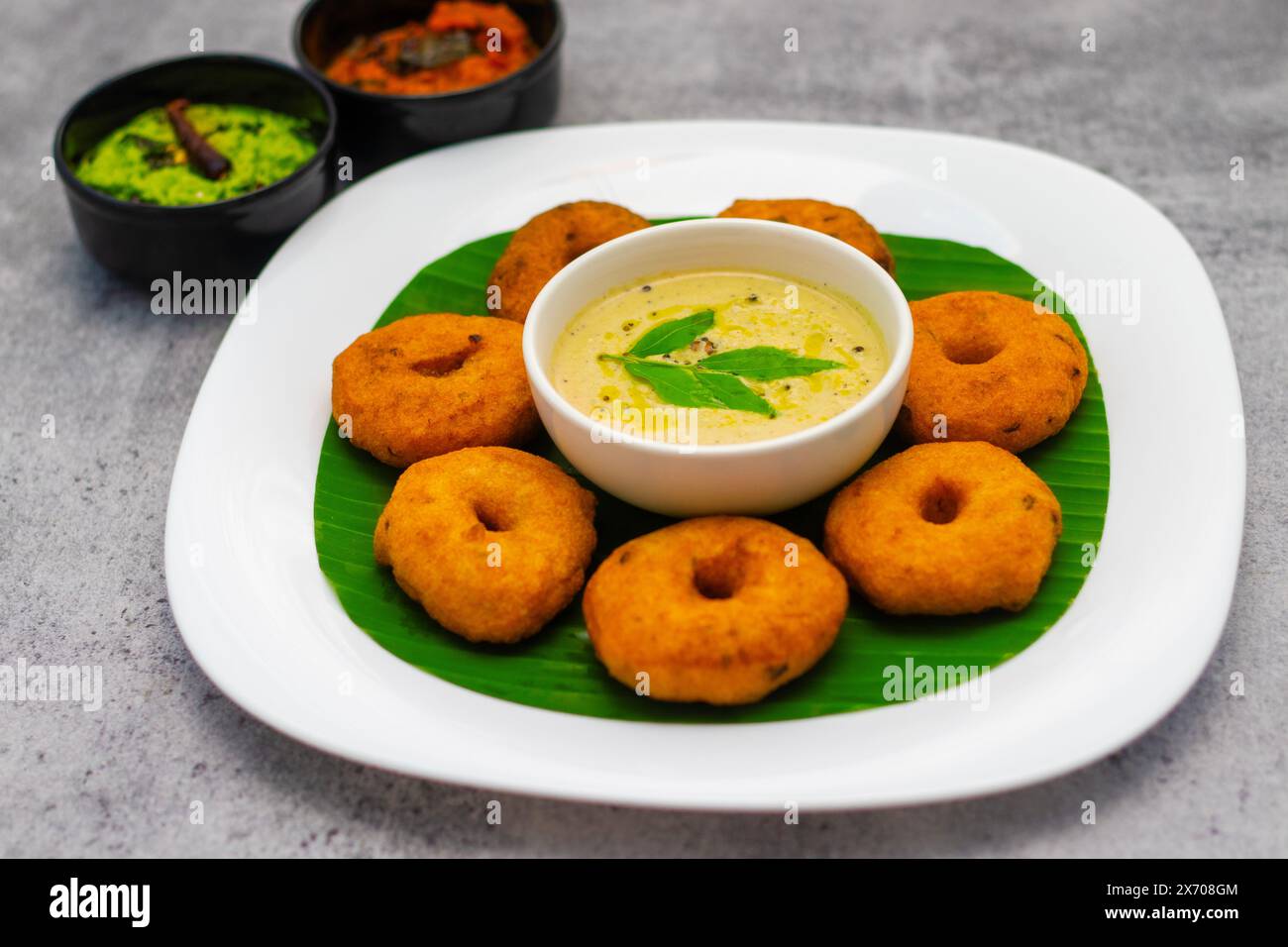 Selektiver Fokus auf das berühmte südindische Essen „Medu Vada“ mit Sambar und Kokosnuss-Chatney. Stockfoto Selektiver Fokus auf das berühmte südindische Essen „Medu Vada“ mit Sambar und Kokosnuss-Chatney. Stockfoto