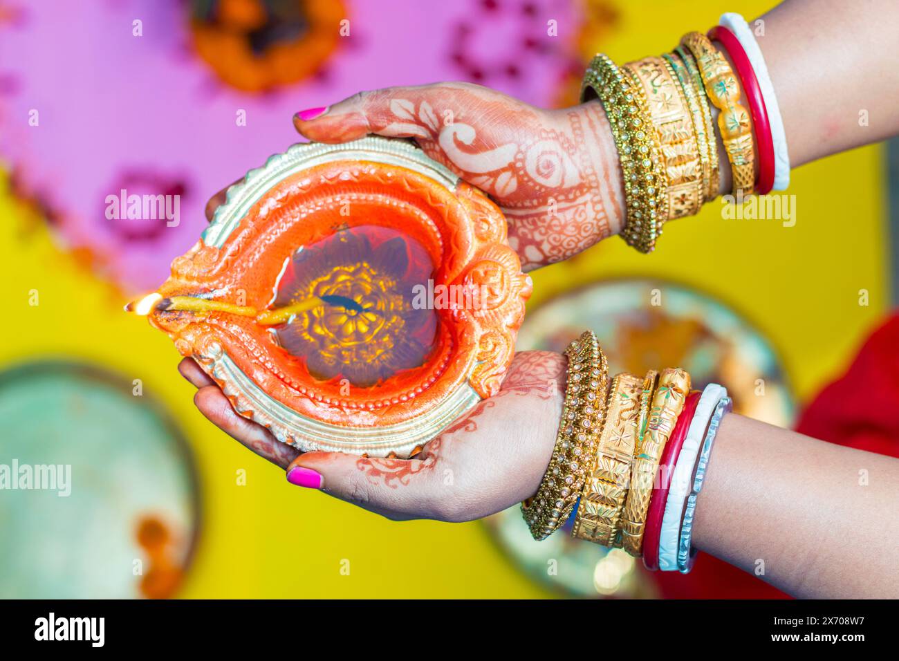 Eine indische Dame hält mit Kerzenlicht Diya auf schwarzem Hintergrund. Stockfoto