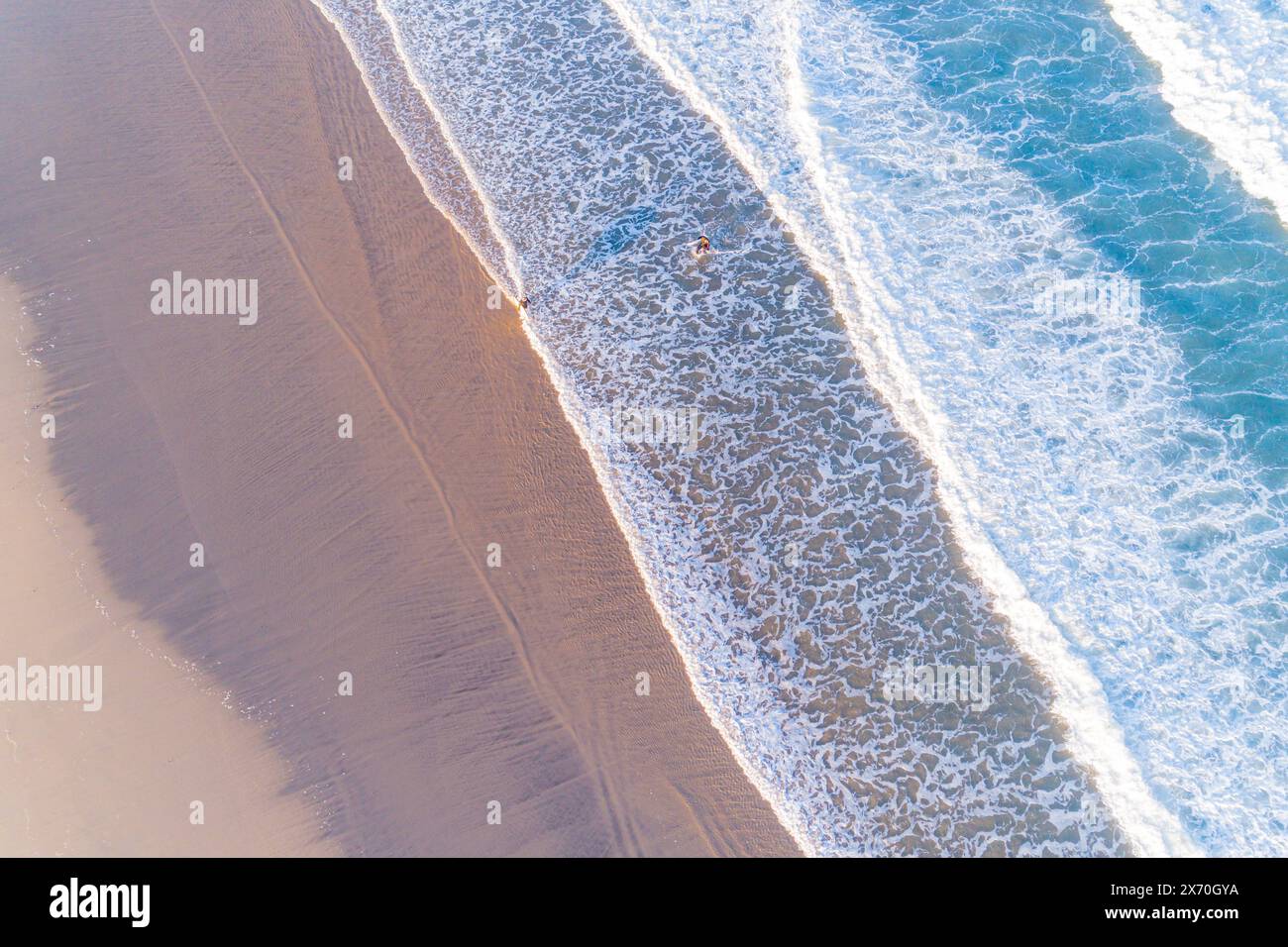 Zwei junge Männer am Strand bei Sonnenaufgang mit ihren Surfbrettern, Surfer genießen den Sommer. Draufsicht mit Drohne Stockfoto