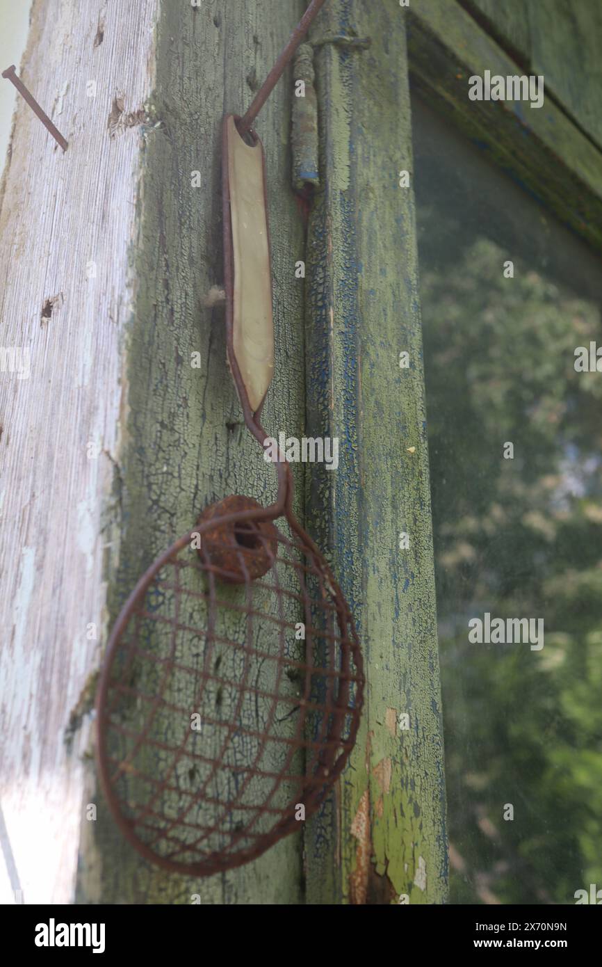Sehr altes Sieb mit rostigem Griff, das an der Wand hängt Stockfoto