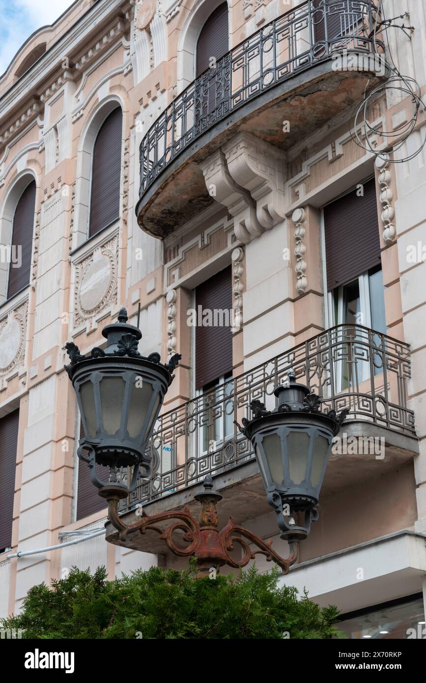 Prunkvolle Straßenlaternen vor einem alten Gebäude mit Balkon in Novi Sad. April 2024. Stockfoto