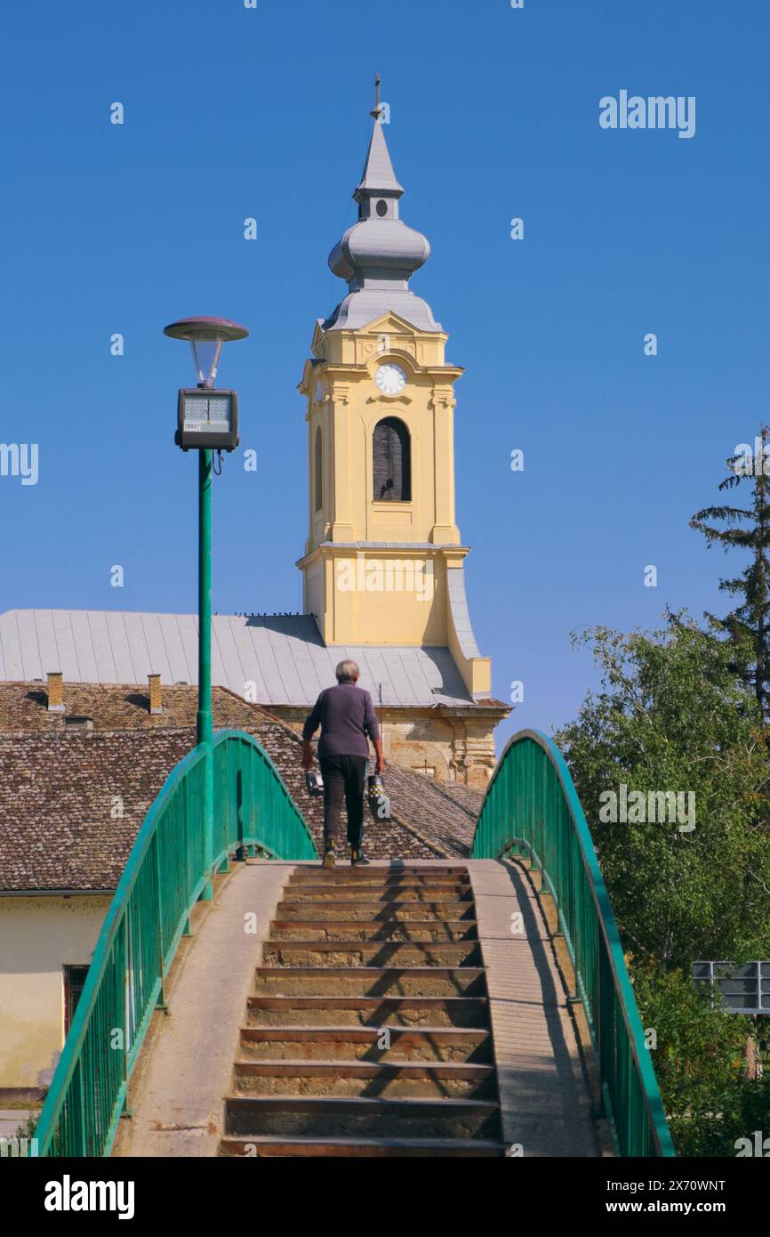 Alte Frau auf der Fußgängerbrücke zur St. Pauls Kirche in Bac, Vojvodina, Serbien Stockfoto