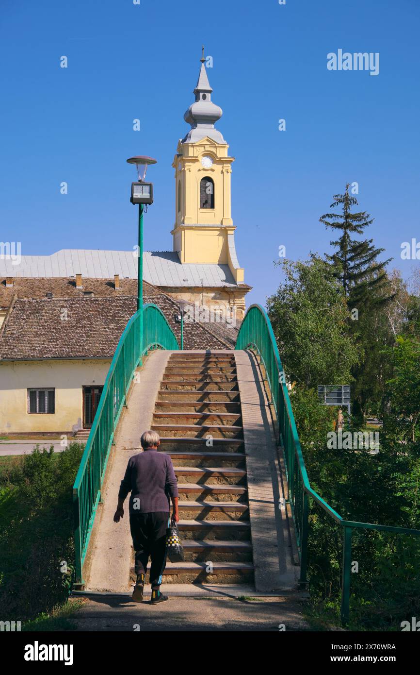 Alte Frau auf der Fußgängerbrücke zur St. Pauls Kirche in Bac, Vojvodina, Serbien Stockfoto