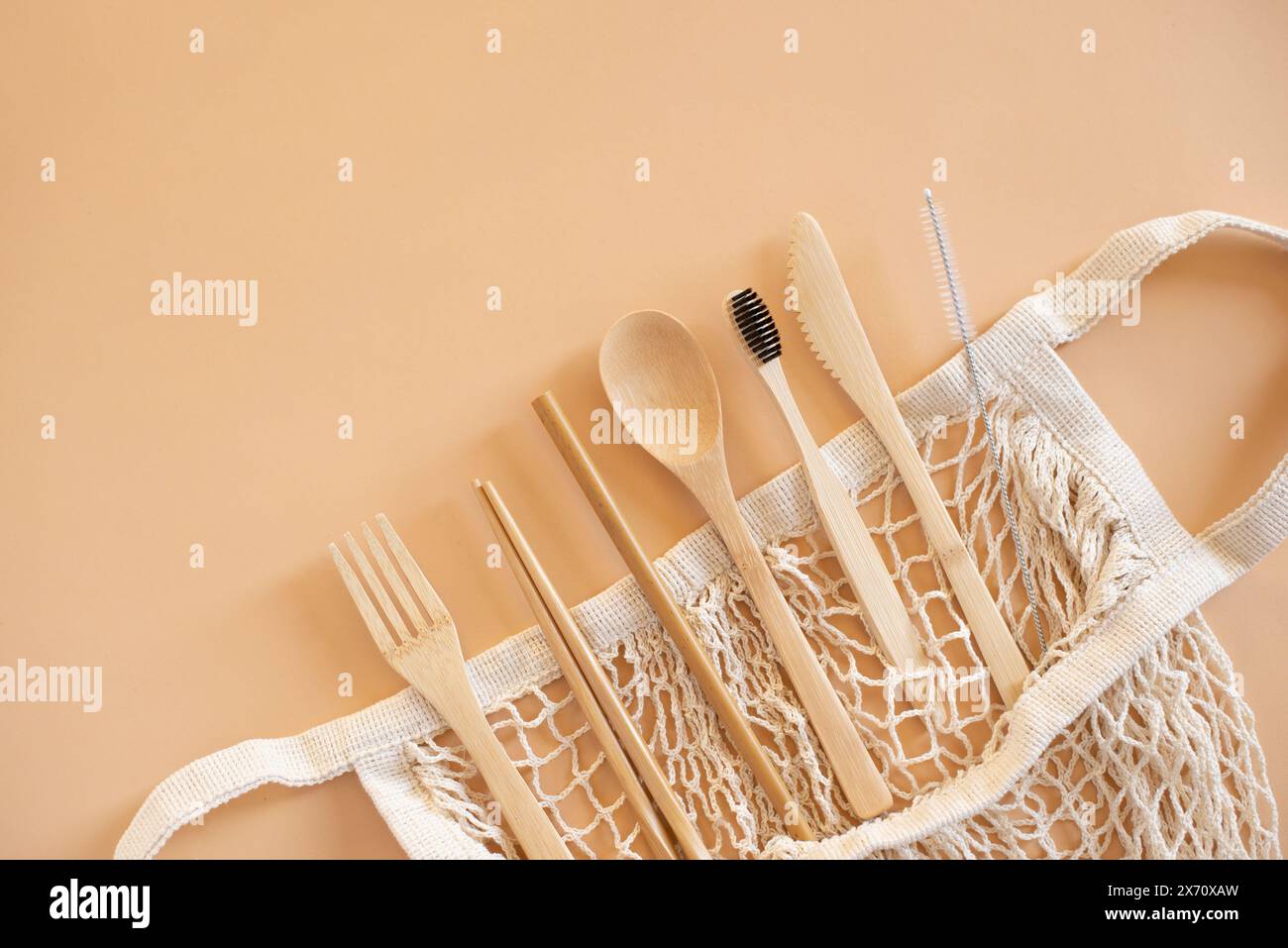 Umweltfreundliche Tasche und Bambusbesteck mit Zahnbürste auf beigefarbenem Hintergrund für grünes Leben und Zero Waste Konzept. Draufsicht. Stockfoto