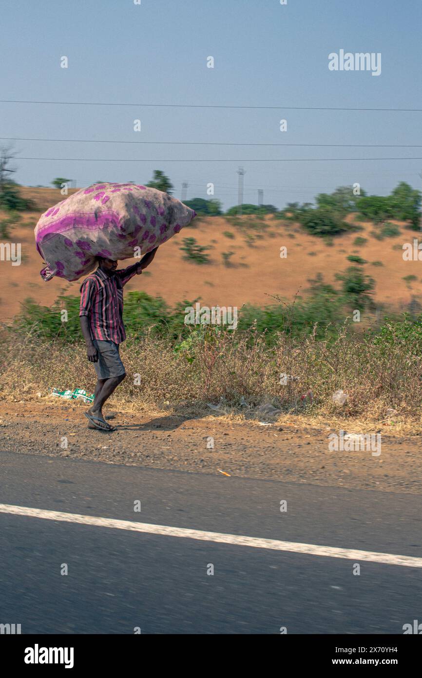 Indischer Mann mit einer Last auf dem Kopf in der Nähe von nashik, maharashtra, indien, Stockfoto