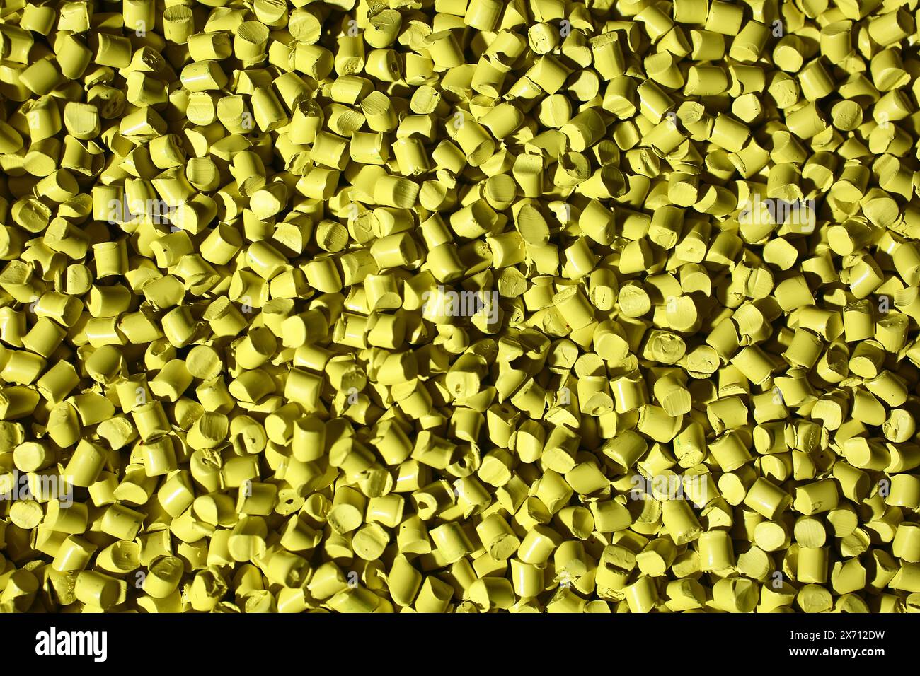 Makrorahmen aus gelbem Kunststoffgranulat. Der Polymerverbund wird in einen Tank zur weiteren Produktion und zum Gießen in Spezialformen gegossen. Stockfoto