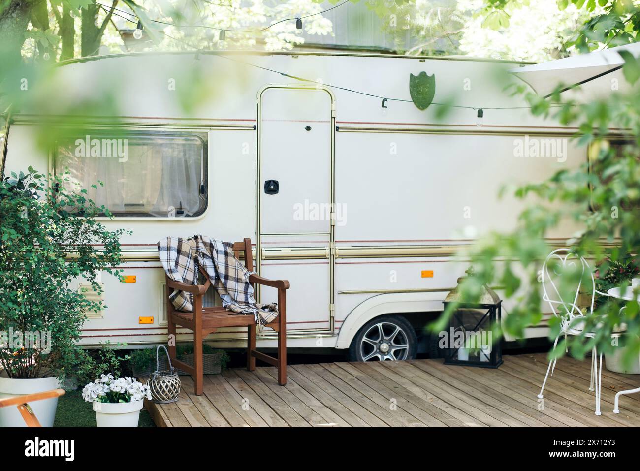 Wohnmobil mit Terrasse, Haus auf Rädern. Campingplatz im Wohnwagen. Wohnwagenhaus auf Rädern in einem grünen Waldgarten. Anhänger. Stockfoto