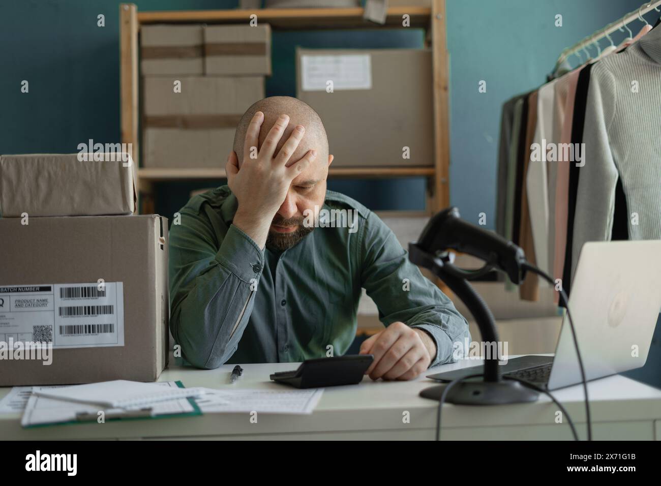 Ein müder Arbeiter bestellt, um Pakete an Kunden zu senden. Probleme kleiner Unternehmen. Stockfoto