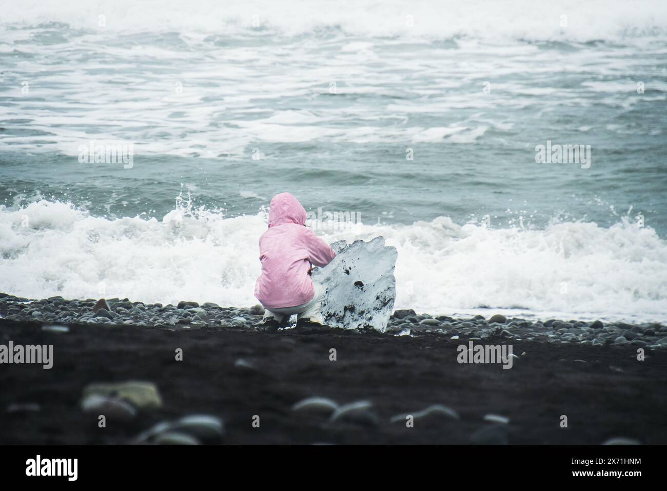 Touristenfrau mit blauem Eisberg am schwarzen Sandstrand von Diamond Beach, Island Stockfoto