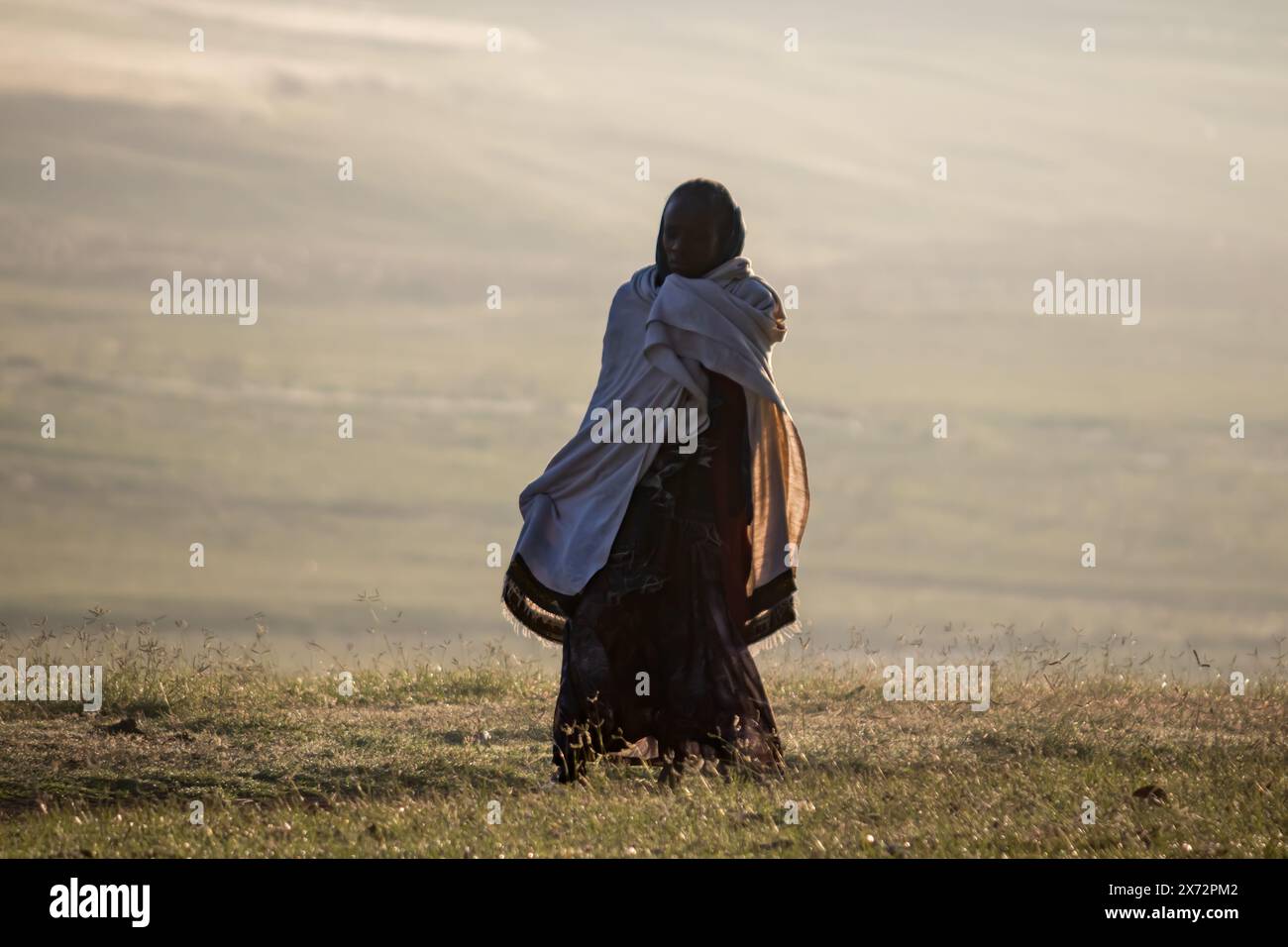 Wunderschöner Blick auf die Landschaft und die Natur Äthiopiens am Morgen, mit der Silhouette einer traditionell gekleideten einheimischen Frau, die durch endlose Täler spaziert Stockfoto