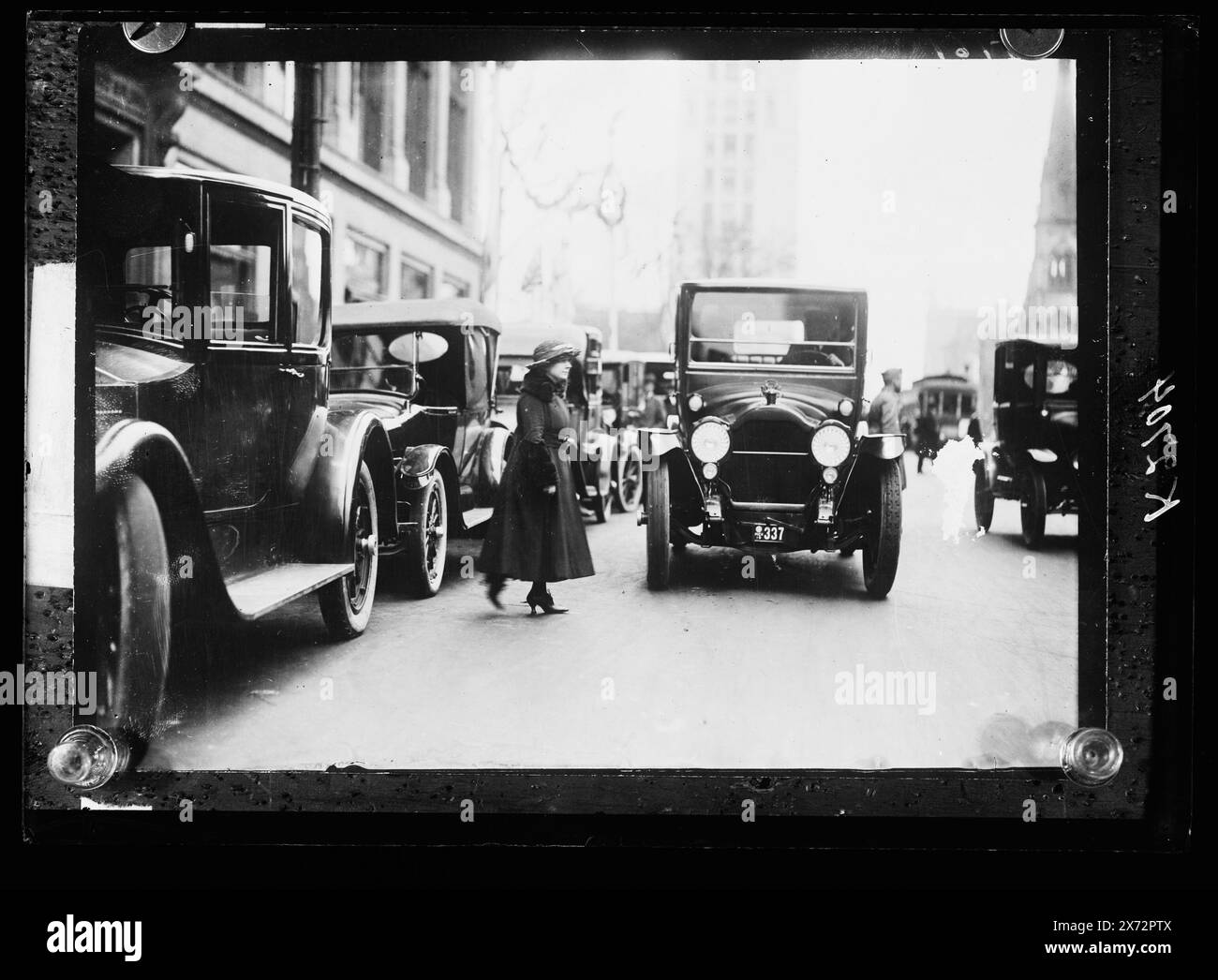 Frau, die vor Autos läuft, mir., Titel vom Kataloger erfunden., wahrscheinlich verwandt mit Negativen D420-2700 bis D420-2706., möglicherweise Detroit, Michigan, und eine Illustration der Verkehrssicherheit., 'mich 19' auf Nummernschild., Detroit Publishing Co.-Nr. K 2704., Geschenk; State Historical Society of Colorado; 1949, Women. , Straßen. , Automobile. , Usa, Michigan. Stockfoto