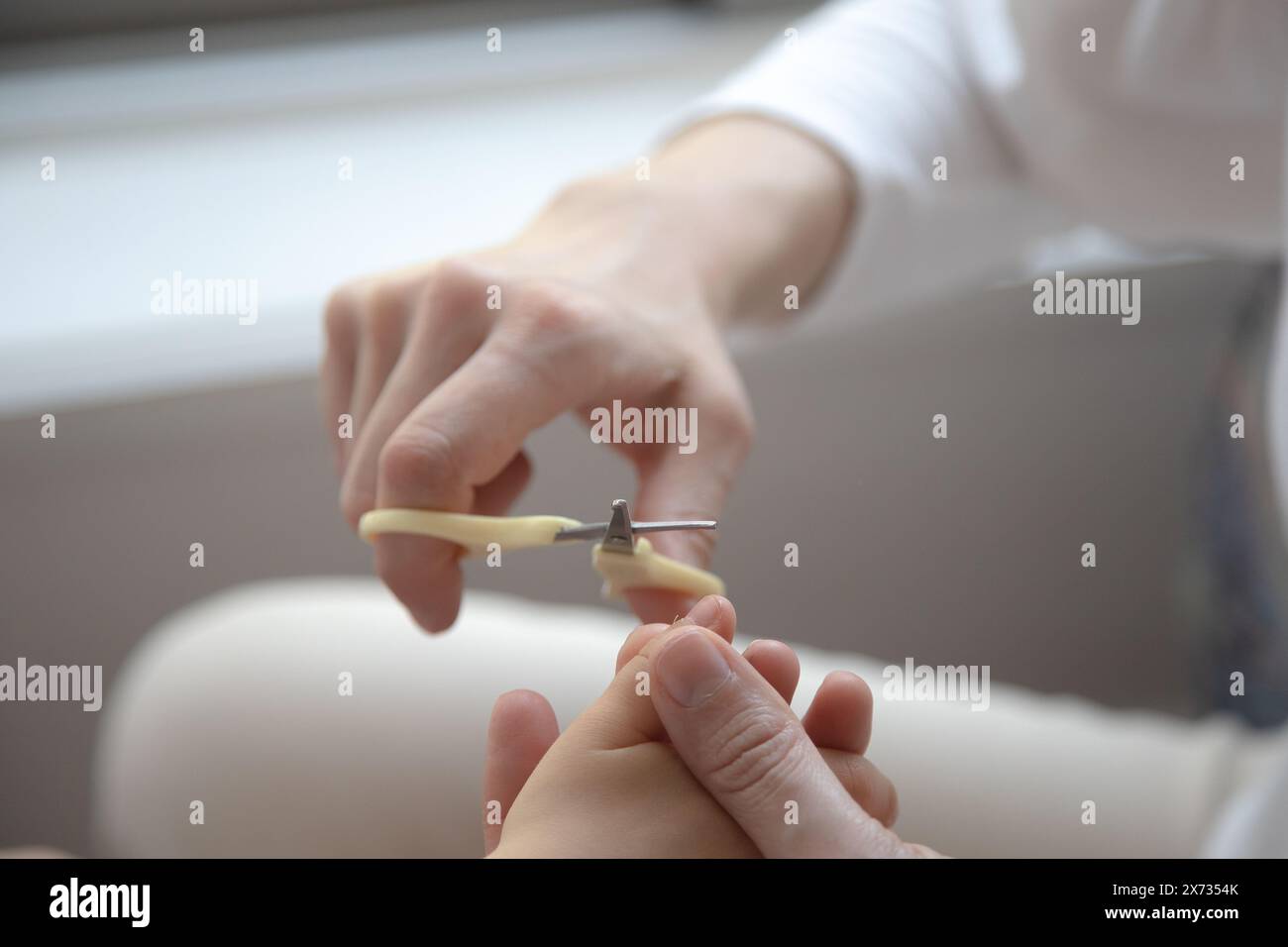 Nahaufnahme eines Erwachsenen, der die Fingernägel eines Kindes sorgfältig trimmt, um einen zarten Moment der Pflege und Pflege hervorzuheben. Stockfoto