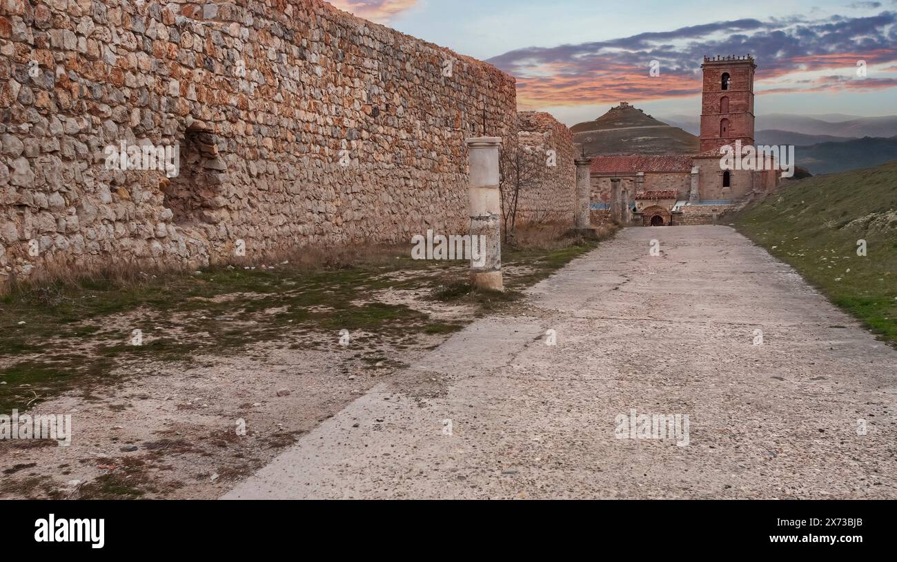 Landschaft mit Blick auf eine Säulenstraße, eine mittelalterliche Steinmauer und die romanische Kirche im Hintergrund im spanischen Dorf Atienza bei Sonnen Stockfoto Landschaft mit Blick auf eine Säulenstraße, eine mittelalterliche Steinmauer und die romanische Kirche im Hintergrund im spanischen Dorf Atienza bei Sonnen Stockfoto