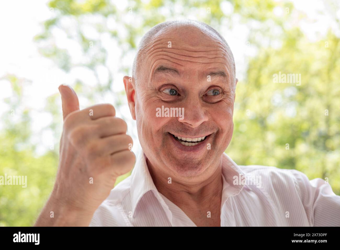 Fröhlicher Seniorenmann mit Augenzwinkern, der die einfachen Freuden des Lebens annimmt, den lebhaften Rentner, der Wärme und ansteckendes Lachen ausstrahlt Stockfoto