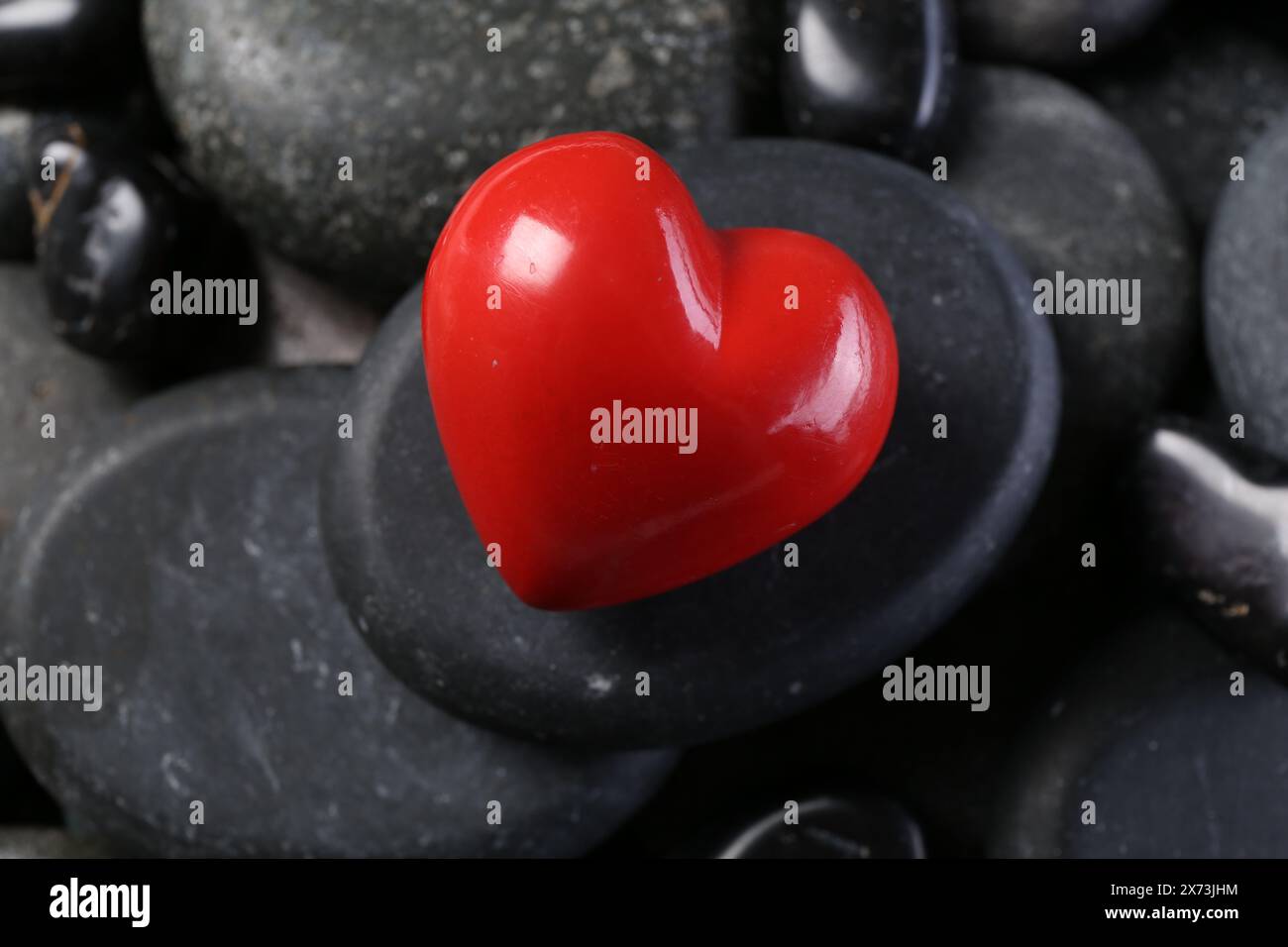 Rotes dekoratives Herz auf Kieselsteinen, Nahaufnahme Stockfoto