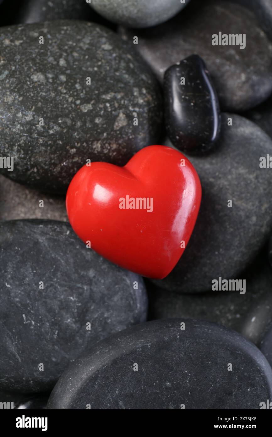 Rotes dekoratives Herz auf Kieselsteinen, Ansicht oben Stockfoto