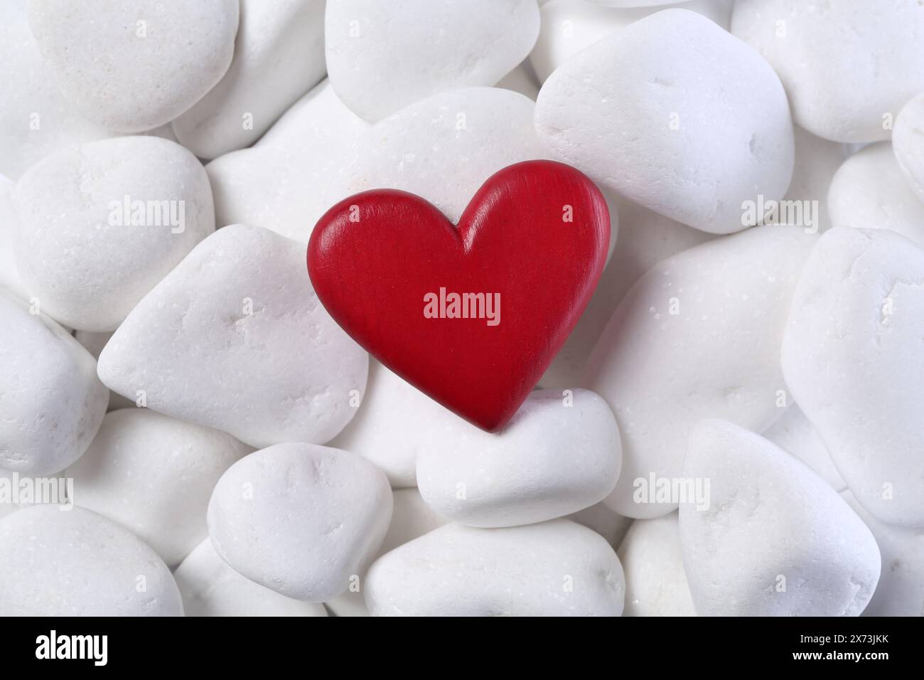 Dekoratives Herz auf weißen Kieselsteinen, Draufsicht Stockfoto