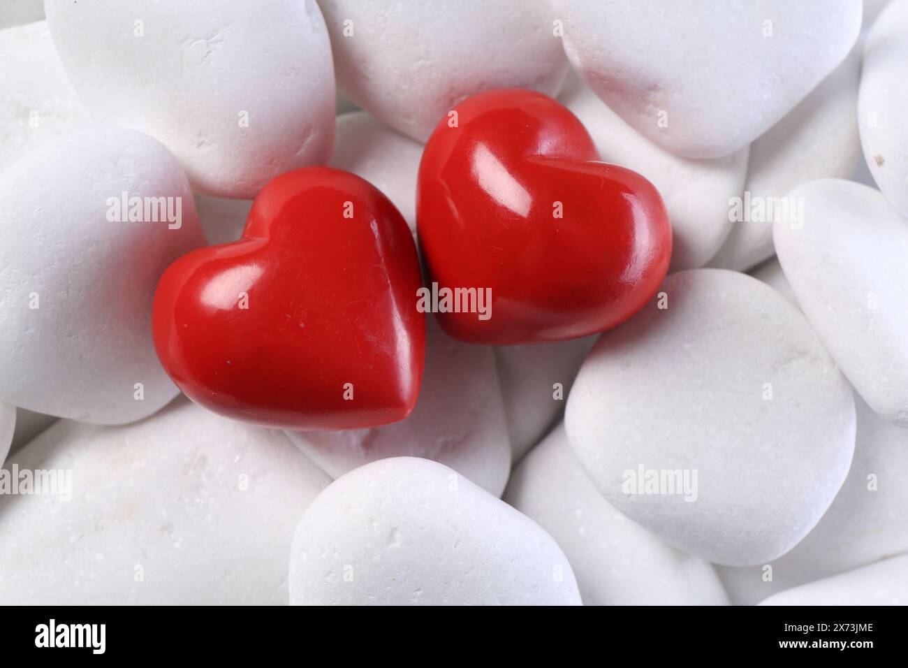 Dekorative Herzen auf weißen Kieselsteinen, oben Stockfoto