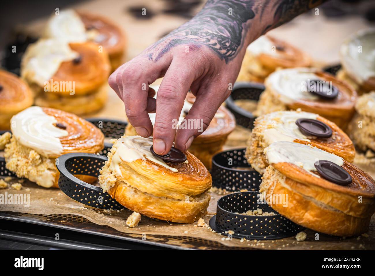 Die Hand des Konditors dekoriert Tartlets mit Schokolade. Zubereitung der Tartlets durch einen professionellen Konditor. Stockfoto