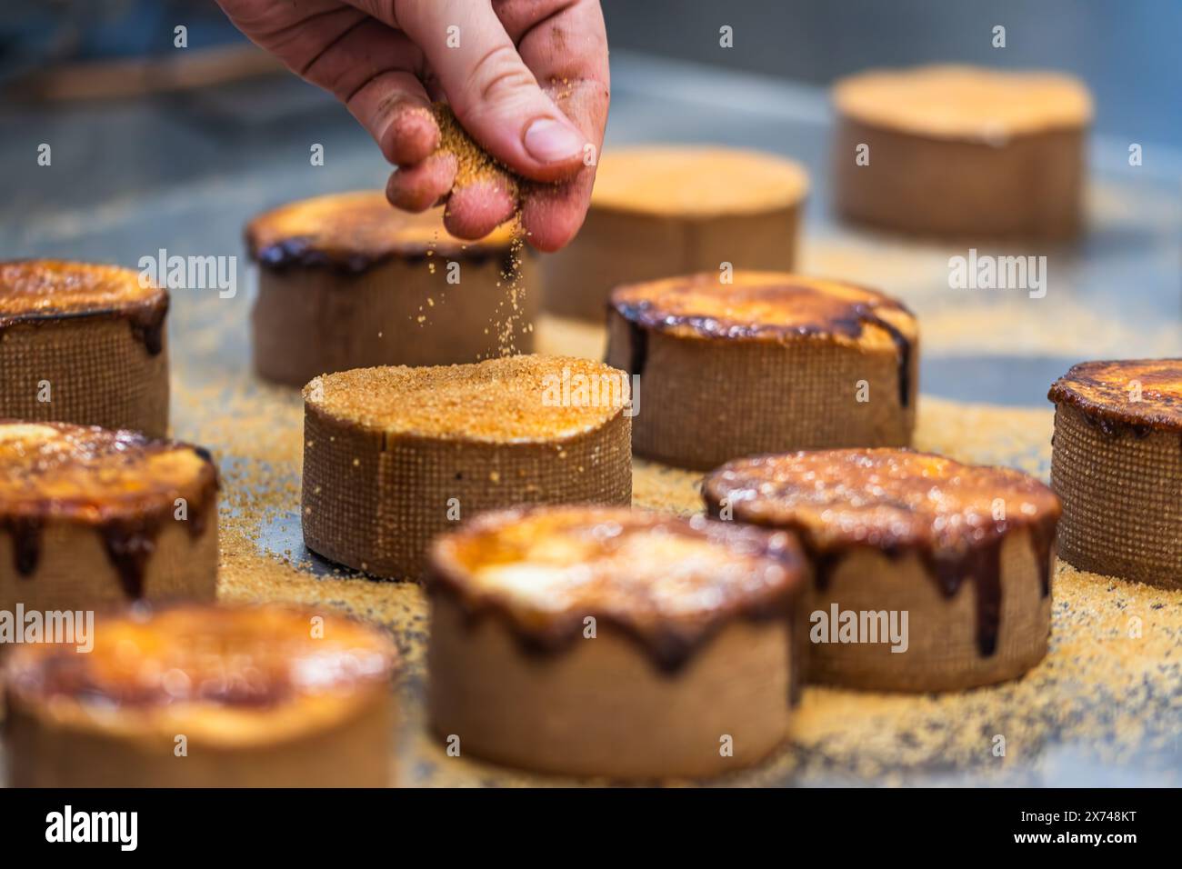 Eine Torte wird mit einem heißen Bügeleisen karamellisiert. Karamelisierungsprozess. Stockfoto