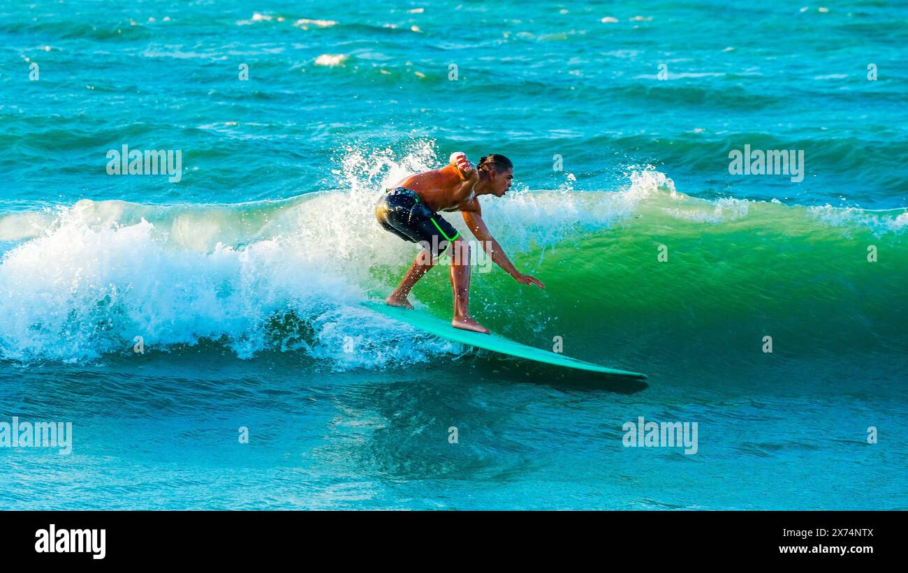 Surfer - Symbolbild: Ritt auf der Welle, blaues Meer, Surfer ohne Shirt, dunkle Badehose, neonfarbene Akzente, hellgrünes Surfbrett, brechende Welle, Spritzwasser, dynamische Pose, Sonniger Tag, leicht bewölkter Himmel, dunkle Haut, lange Haare, Fokus auf Surfen, Actionaufnahme, Ozean, Hintergrund, Wasser, Sport, Freizeit, Outdoor-Aktivität, Balance, Geschicklichkeit, Adrenalin, Geschwindigkeit, Sommer, Strand, Abenteuer, Surfen, Wellenreiten, Wassersport, Meeresbrise, Natur. *** Surfer Symbol Bild auf der Welle reiten, blaues Meer, Surfer ohne Hemd, dunkle Badehosen, Neonakzente, hellgrau Stockfoto