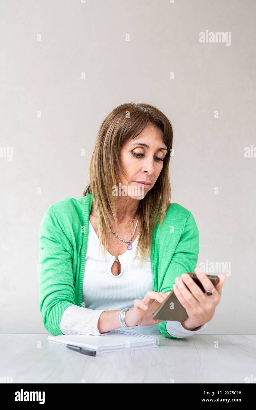 Porträt einer mittelerwachsenen Frau, die auf ihrem Smartphone surft Stockfoto