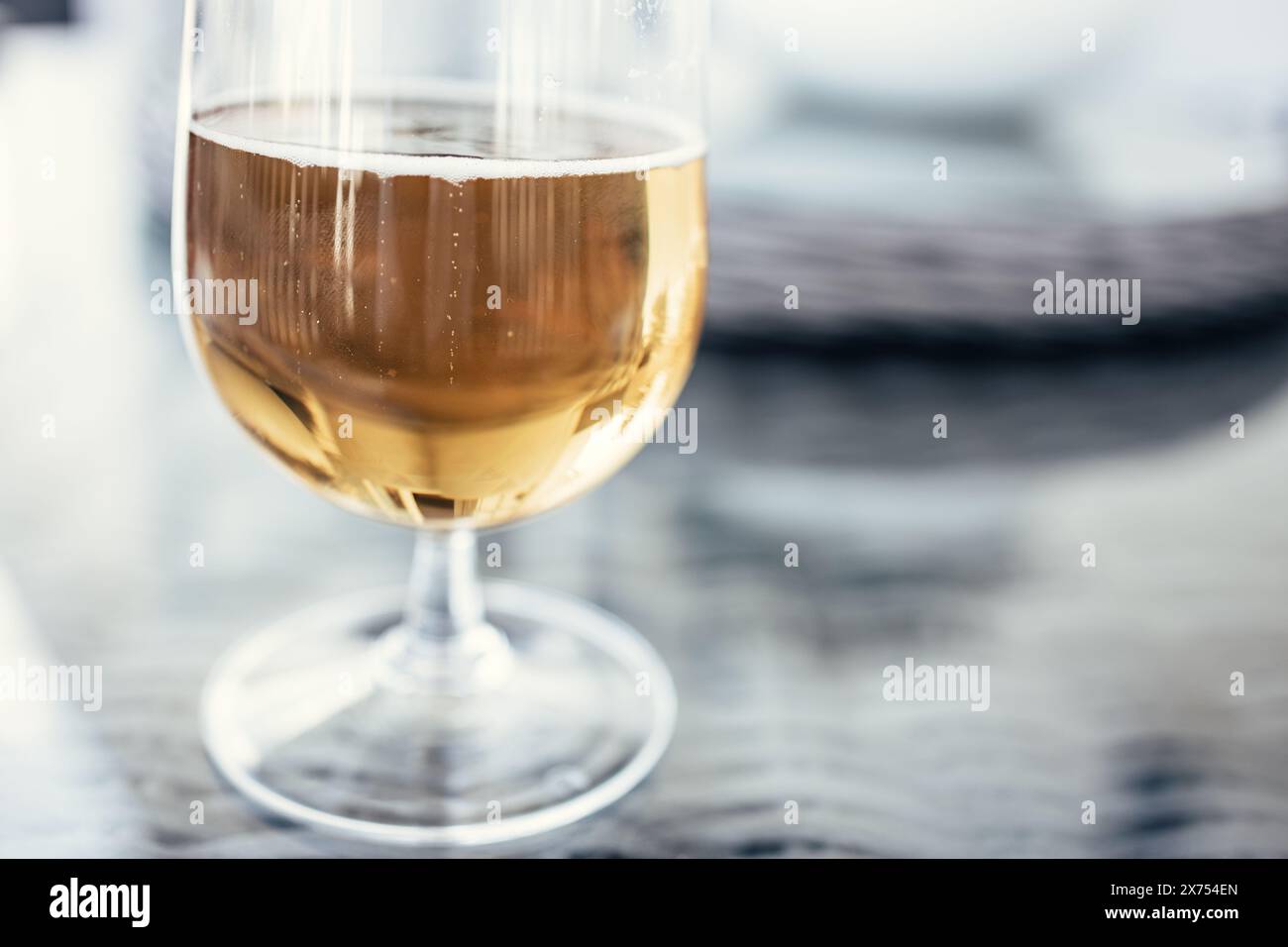 Der Boden eines halb betrunkenen Glases Bier auf einem Glastisch Stockfoto