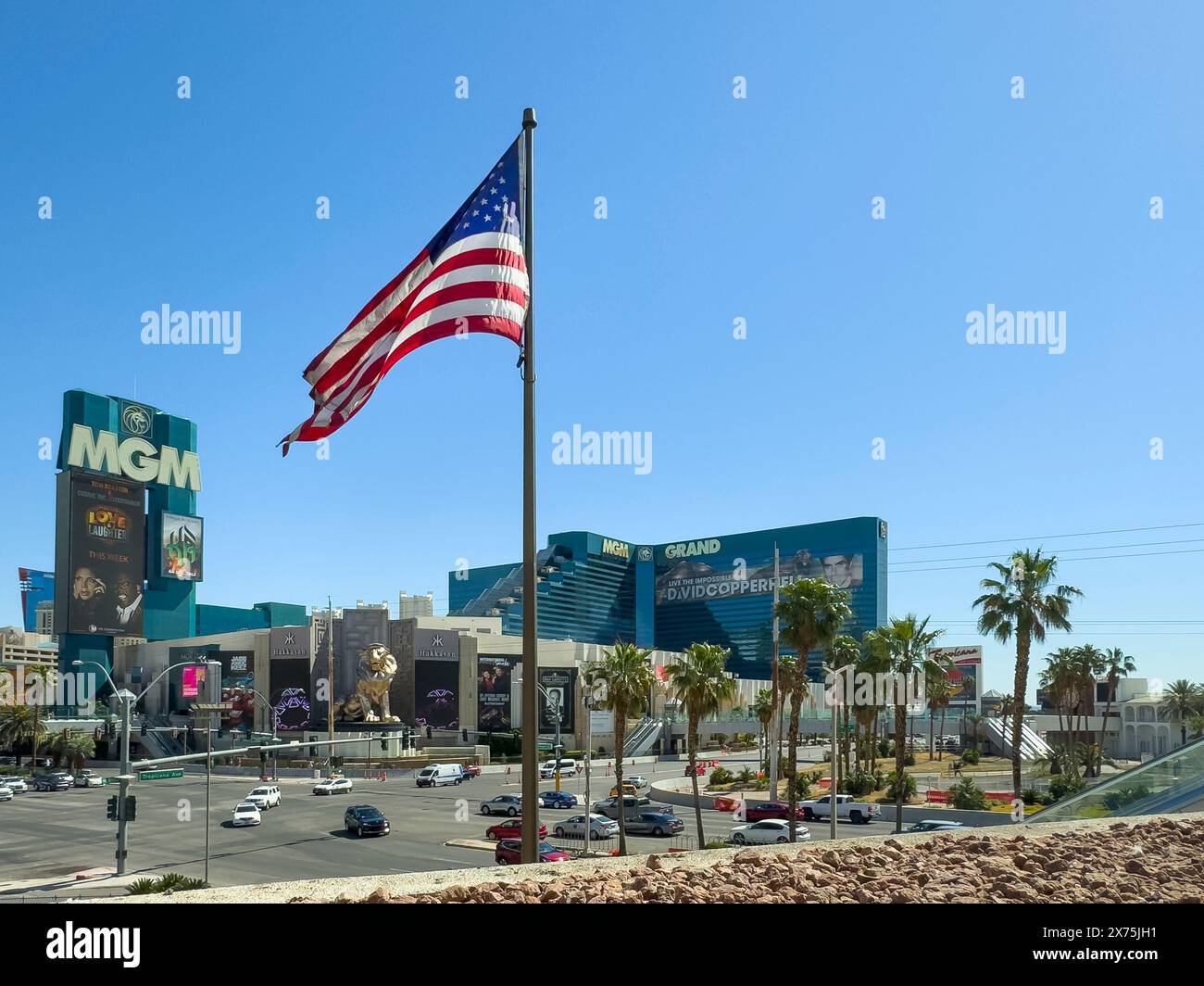 Las Vegas, NV, USA - 12. Mai 2024: Amerikanische Flagge über dem grünen MGM Grand Hotel unter blauem Himmel. Kreuzung Tropicana und S. Las Vegas Blvds. Autos und Stockfoto