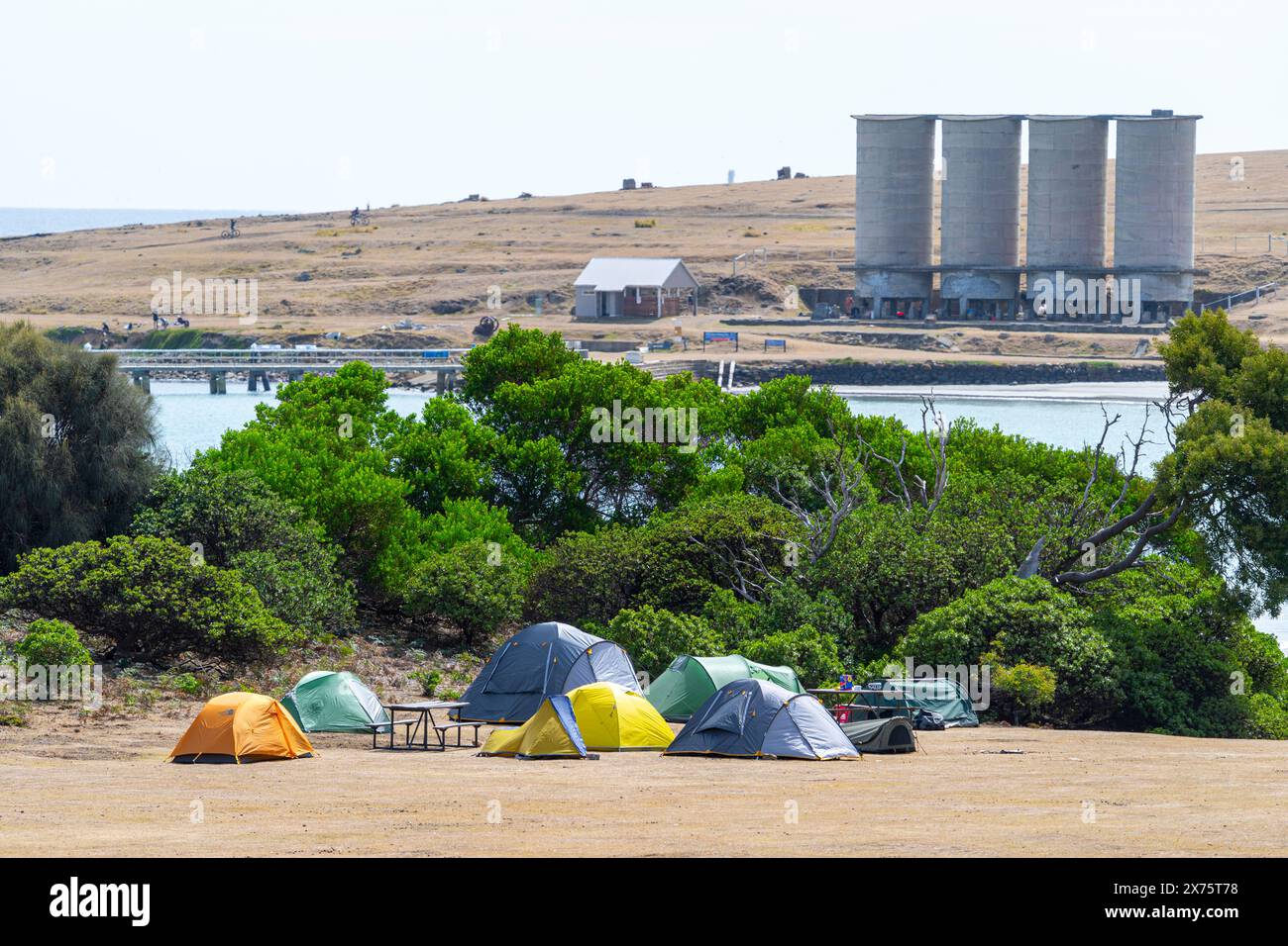 Zelte auf dem Campingplatz Darlington Bay mit Steg und Zementsilos im Hintergrund, Maria Island, Tasmanien Stockfoto