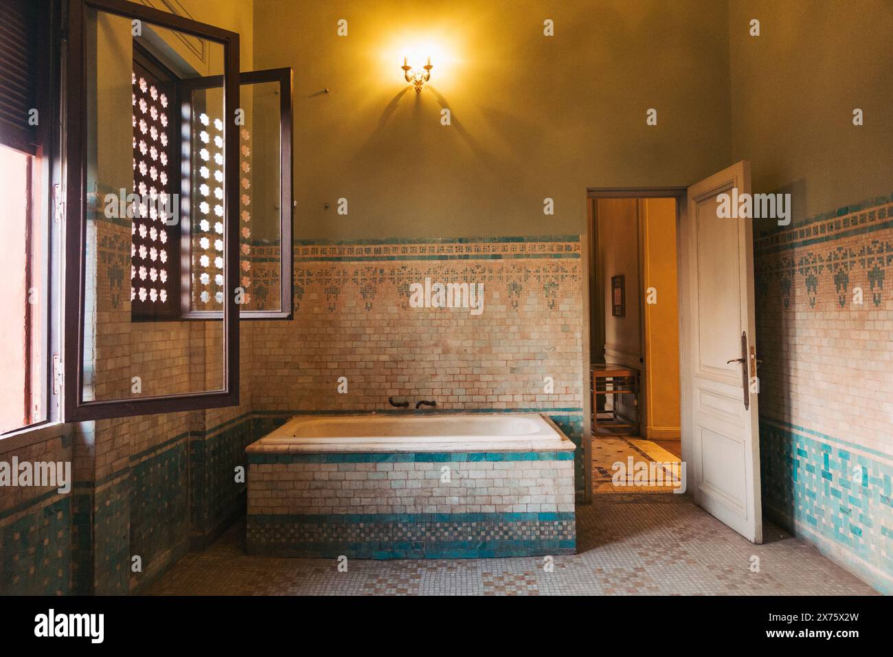 Historisches Badezimmer im Baron Empain Palace in Heliopolis mit komplexen Mosaikfliesen, eingebauter Badewanne und traditionellen Holzfenstern Stockfoto