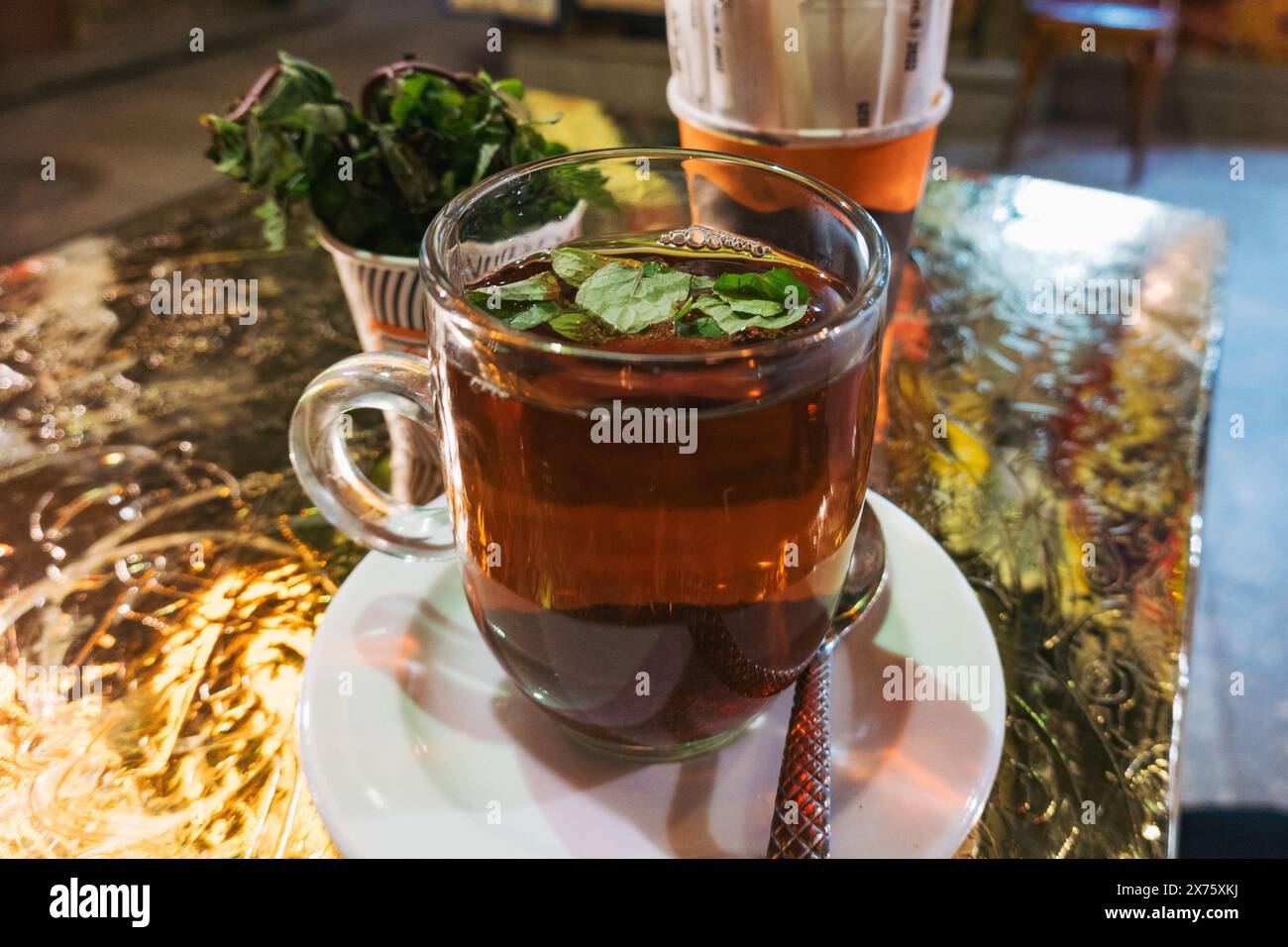 Traditioneller ägyptischer Pfefferminztee in einer Glasschale auf einem Café-Tisch, der die warme Atmosphäre und die lokale Teekultur einfängt Stockfoto