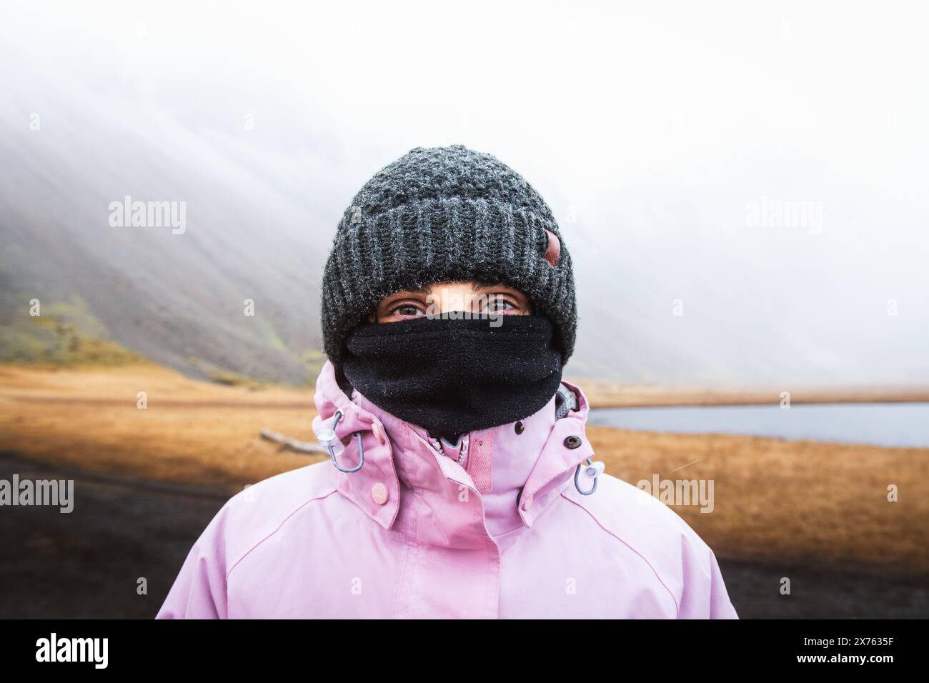 Nahaufnahme einer kaukasischen Frau mit dunklen Augen in warmer Kleidung stehen Sie in die Kamera. Besuchen Sie isländische Touristenattraktionen bei widrigem isländischem Wetter Stockfoto