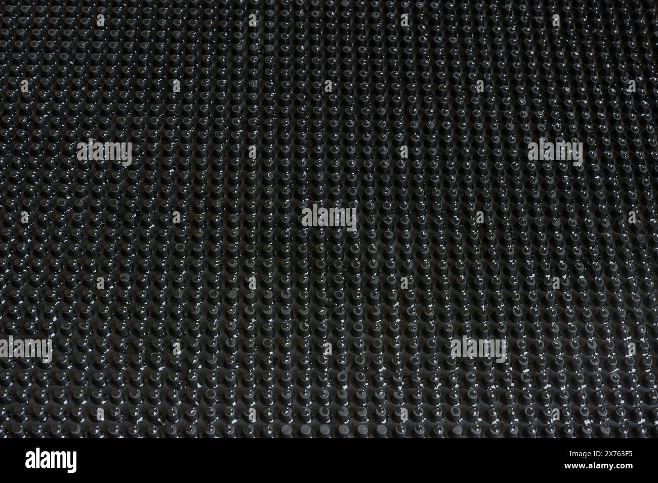 Abstraktes schwarzes Punktgitter im Hintergrund mit heller Wassertropfenbeleuchtung. Stockfoto