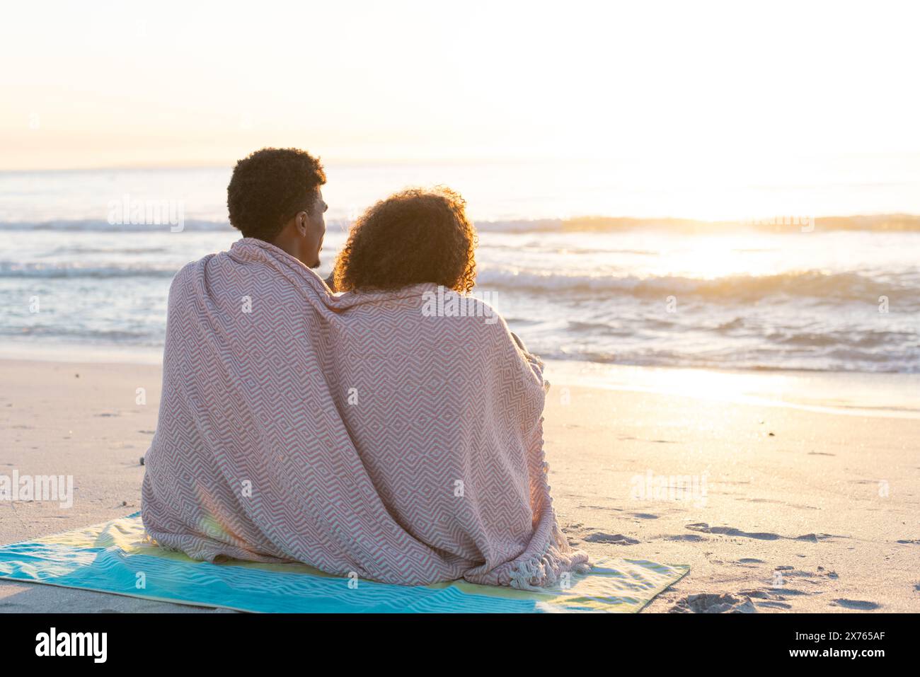 Am Strand saßen diverse Paare dicht unter der Decke und beobachteten den Sonnenuntergang Stockfoto