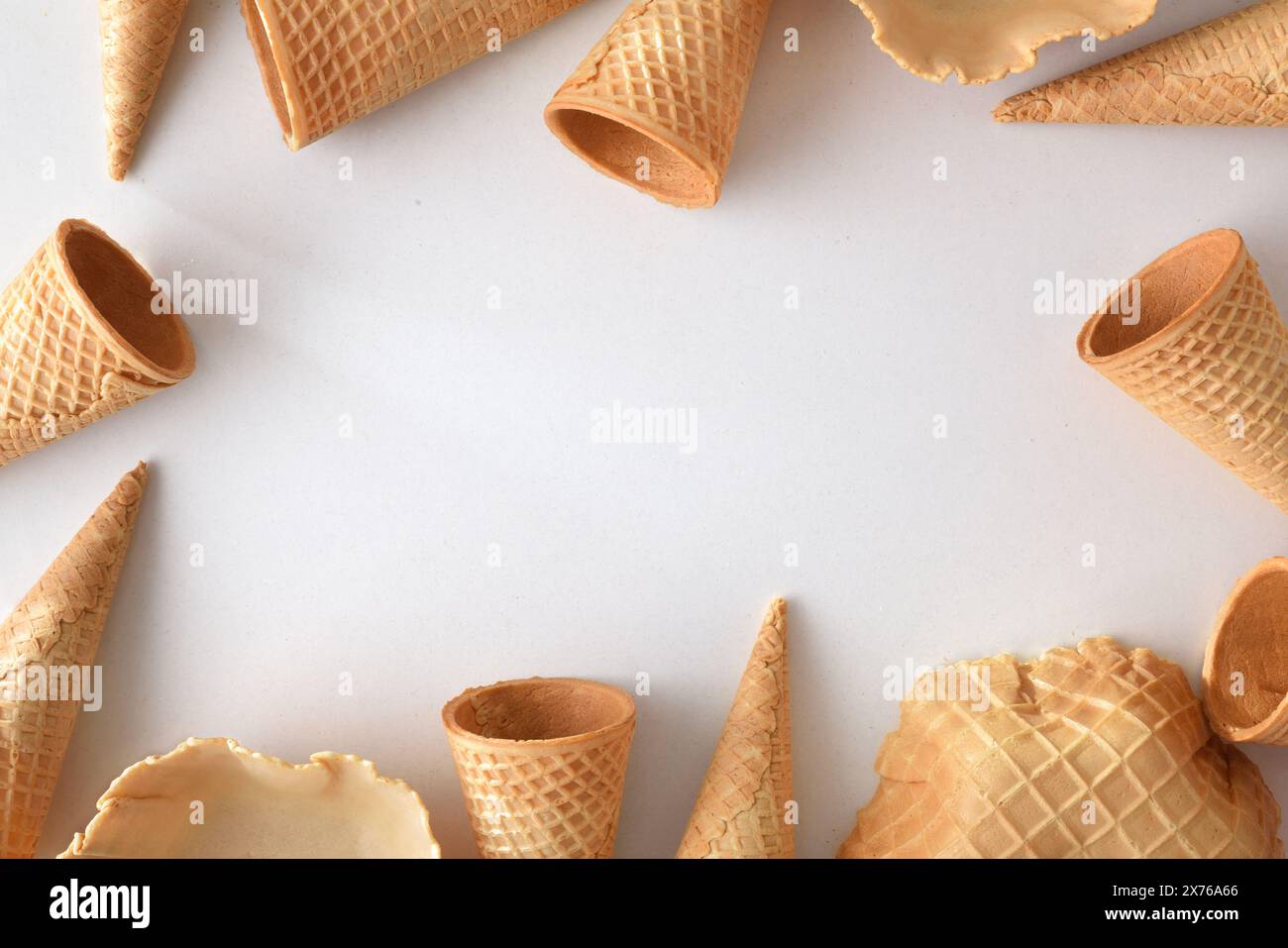 Rahmen mit kegelförmigen und schalenförmigen Waffeln für Eis auf weißem Tisch. Draufsicht. Stockfoto