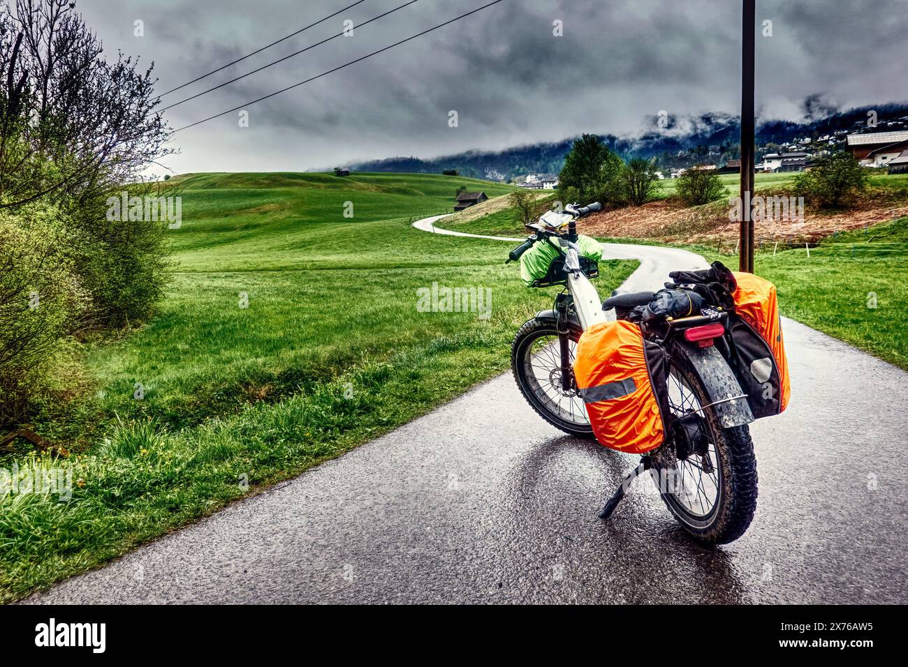 Schwer beladenes E-Fatbike auf einem Radweg in einem österreichischen Alpental bei regnerischem Wetter Stockfoto
