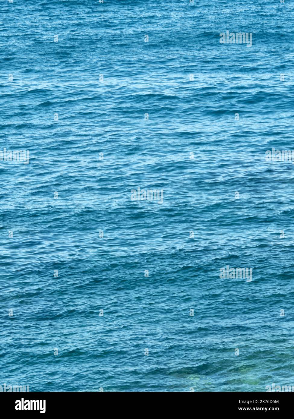 Vertikales dunkelblaues Meer wackelt Hintergrund. Die Meeresoberfläche ist vom Wind zerknittert. Wasserkulisse. Aquatische Textur. Ästhetische Handytapete. Stockfoto