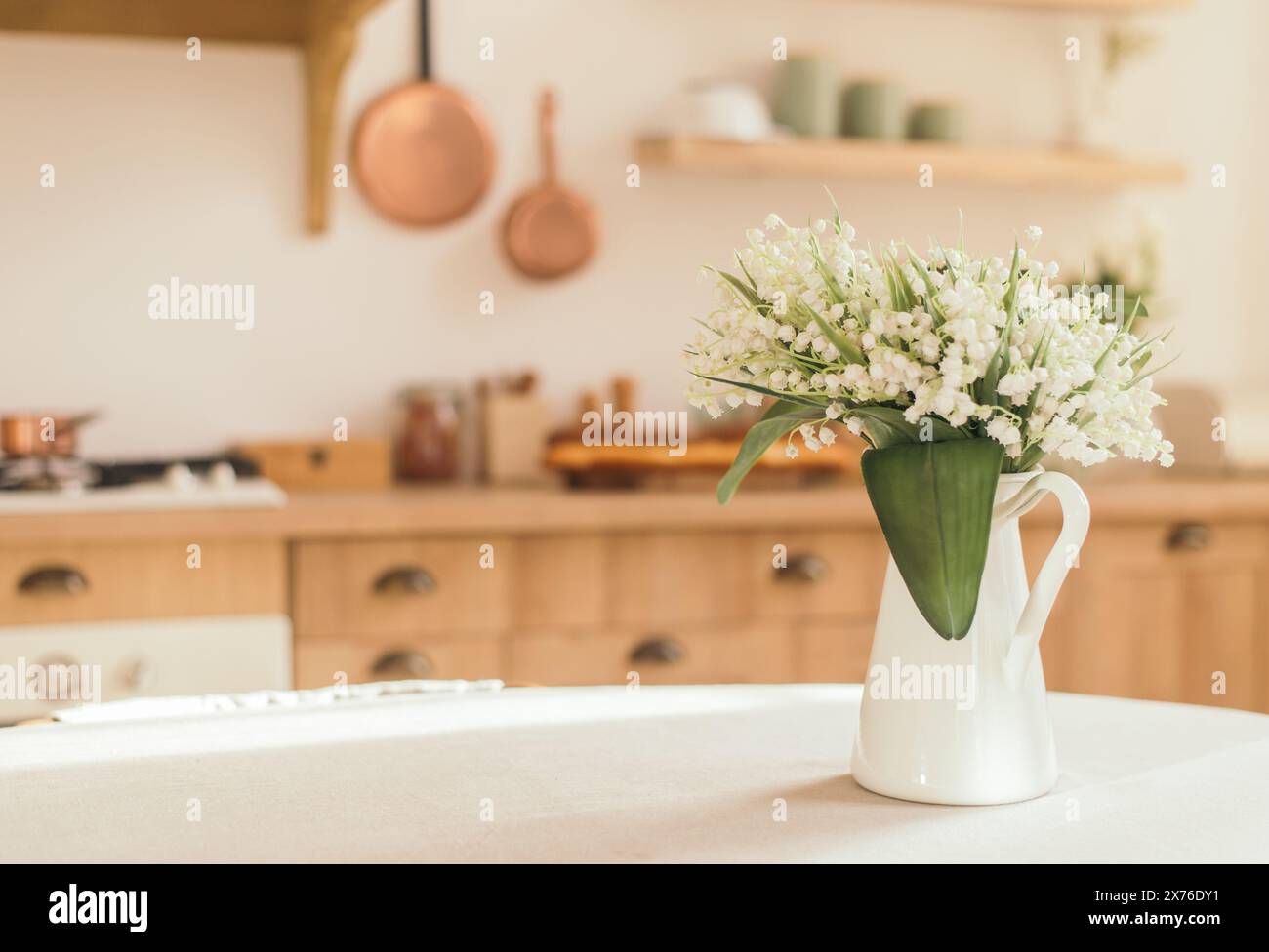 Blumenstrauß von Frühlingsblüten von Lilien des Tales in einer Vase auf dem Küchentisch. Leichter skandinavischer Stil. Muttertag. März, Internatio Stockfoto