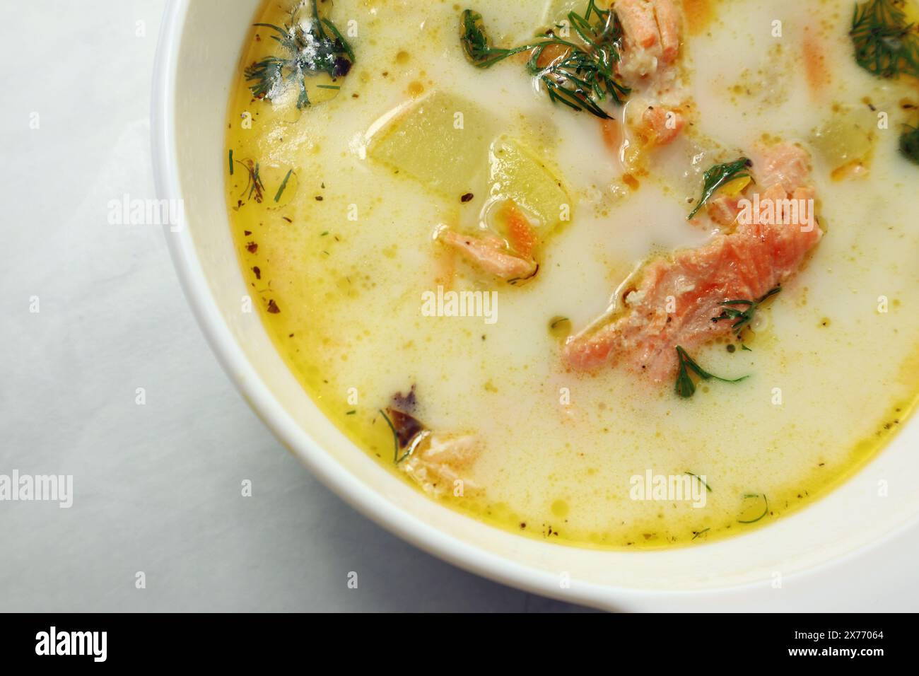 Finnische Sahnesuppe mit Lachs, Kartoffeln, Zwiebeln und Karotten in einer Schüssel auf dem Holztisch, selektiv fokussiert Stockfoto