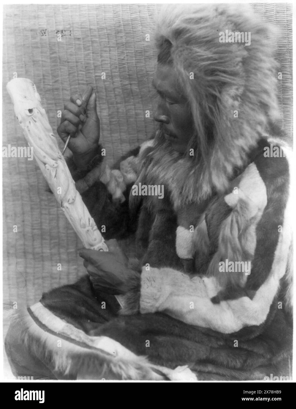 Der Elfenbeinschnitzer Nunivak, Titel aus Artikel., ist Teil von Edward S. Curtis Collection., veröffentlicht in: The North American Indian / Edward S. Curtis. [Seattle, Washington] : Edward S. Curtis, 1907-30, v. 20, S. 86. Indians of North America, Arts & Crafts, Alaska, Nunivak Island, 1920-1930. , Eskimos, Arts & Crafts, 1920-1930. , Pelzbekleidung, 1920-1930. , Elfenbeinschnitzerei, 1920-1930. Stockfoto
