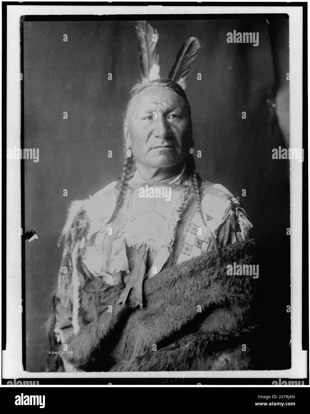 Gelbes Pferd Yanktonai, halblanges Porträt, stehend, leicht nach rechts gerichtet, mit langen Zöpfen, zwei Adlerfedern im Haar, in Büffelhaut gehüllt, Edward S. Curtis Collection 2456–05., veröffentlicht in: The North American Indian / Edward S. Curtis. [Seattle, Washington] : Edward S. Curtis, 1907-30, v. 3, S. 124. Gelbes Pferd. Indianer von Nordamerika, Kleidung & Kleidung, 1900-1910. , Yanktonai Indians, Kleidung & Kleidung, 1900-1910. Stockfoto