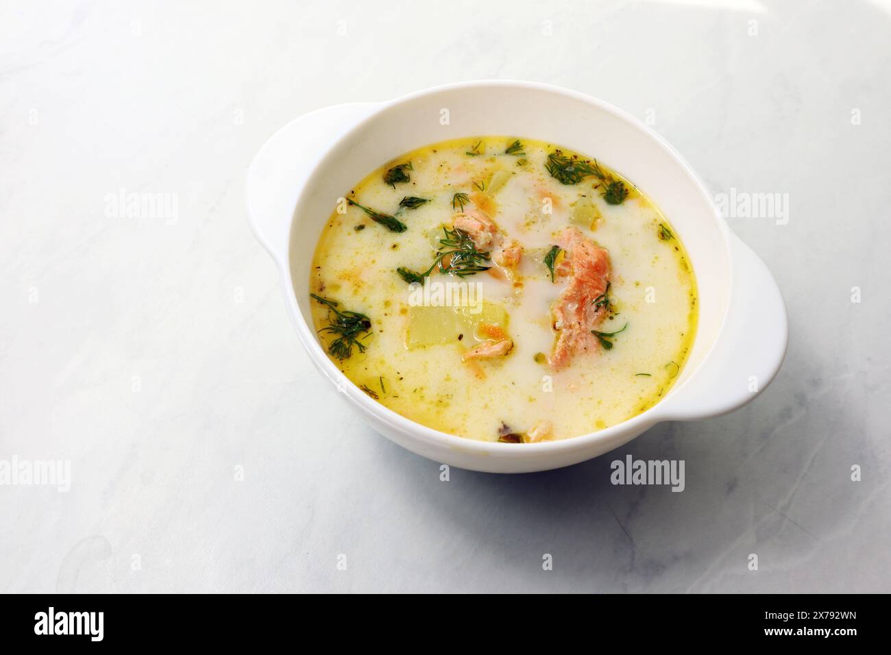 Finnische Sahnesuppe mit Lachs, Kartoffeln, Zwiebeln und Karotten in einer Schüssel auf dem Holztisch, selektiv fokussiert Stockfoto